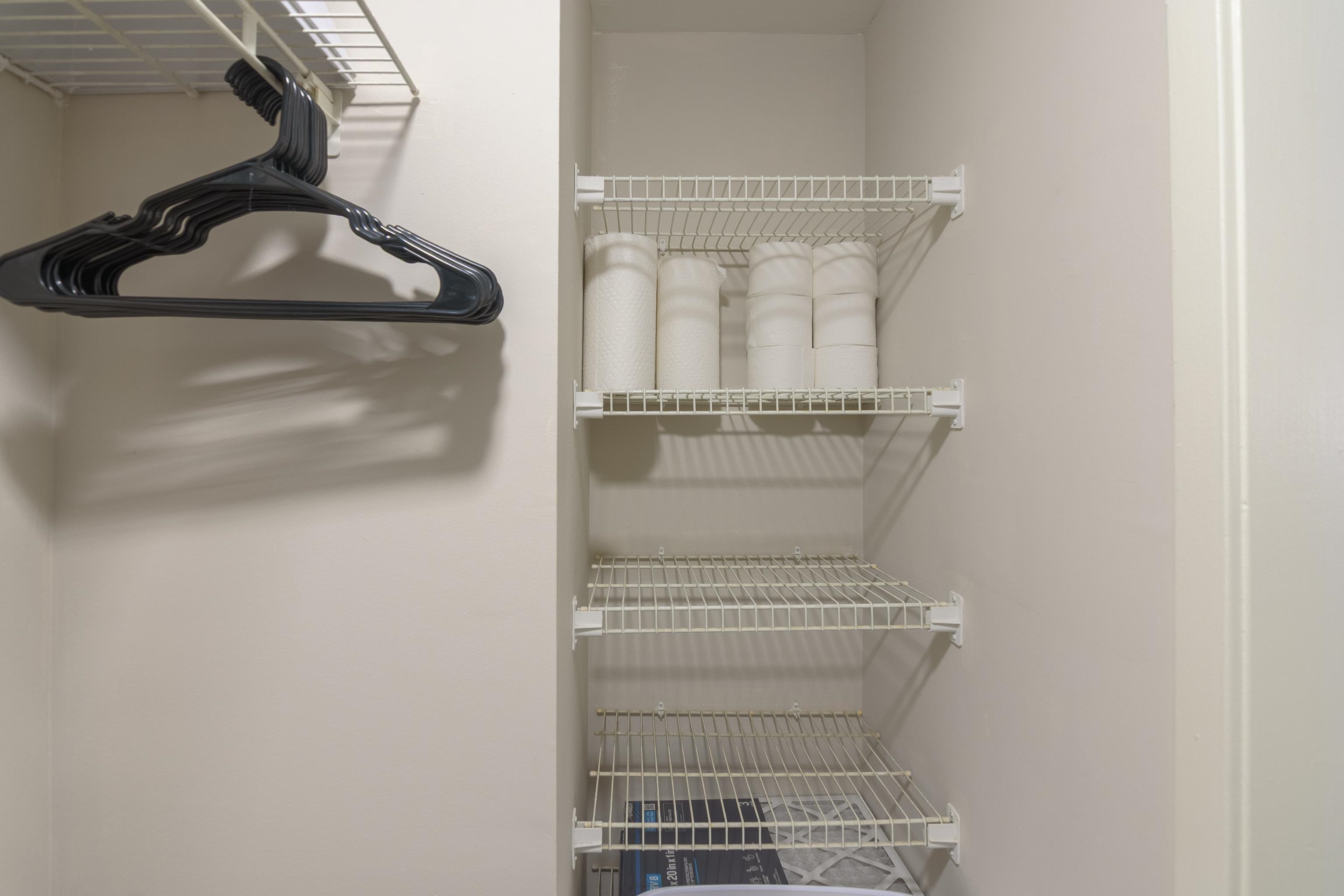 Walk-in closet with wire shelving, black hangers, and folded white towels.