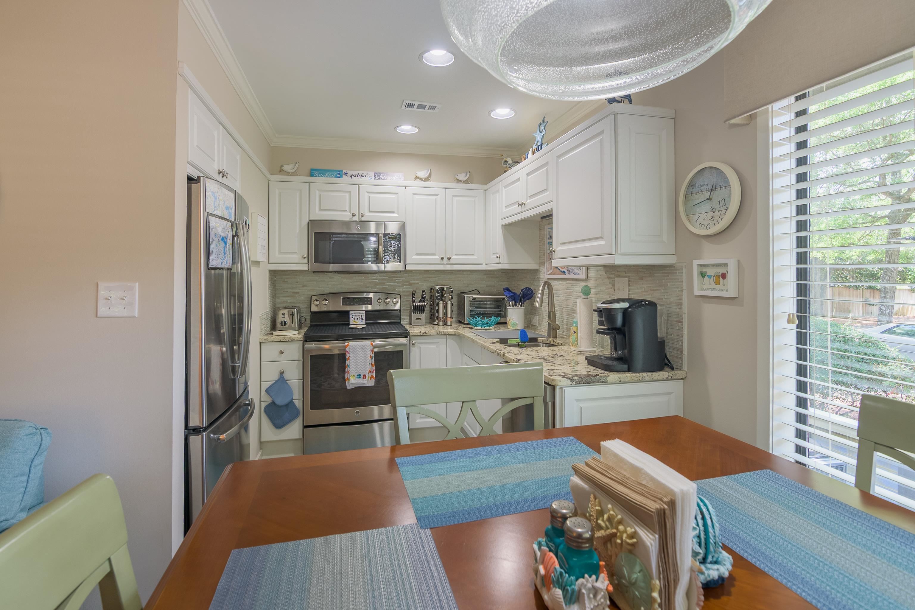 Kitchen with white cabinetry, stainless appliances, and a dining table set with blue placemats.