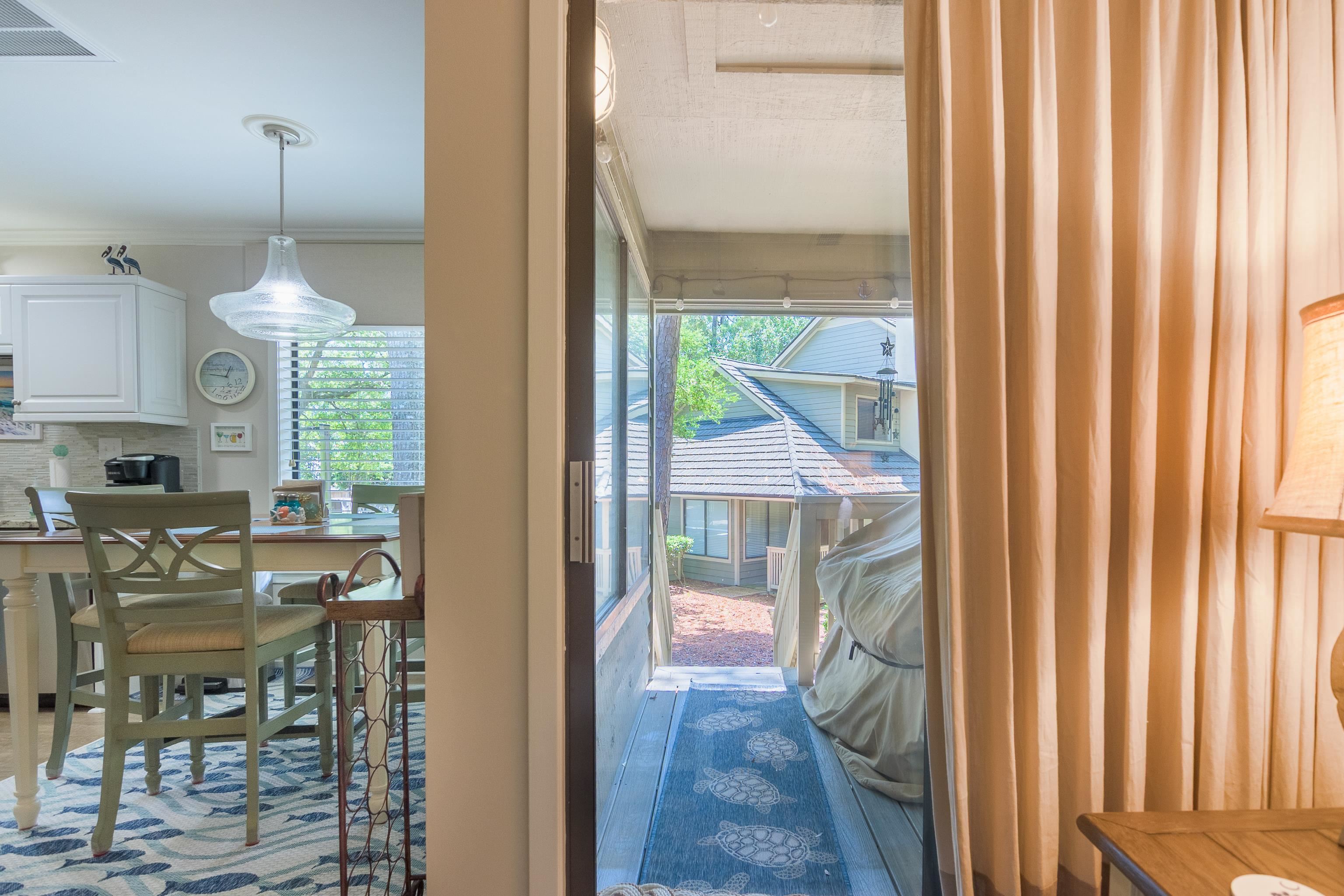 Dining area beside a screened porch with a blue turtle-patterned runner and neighboring rooftops beyond.