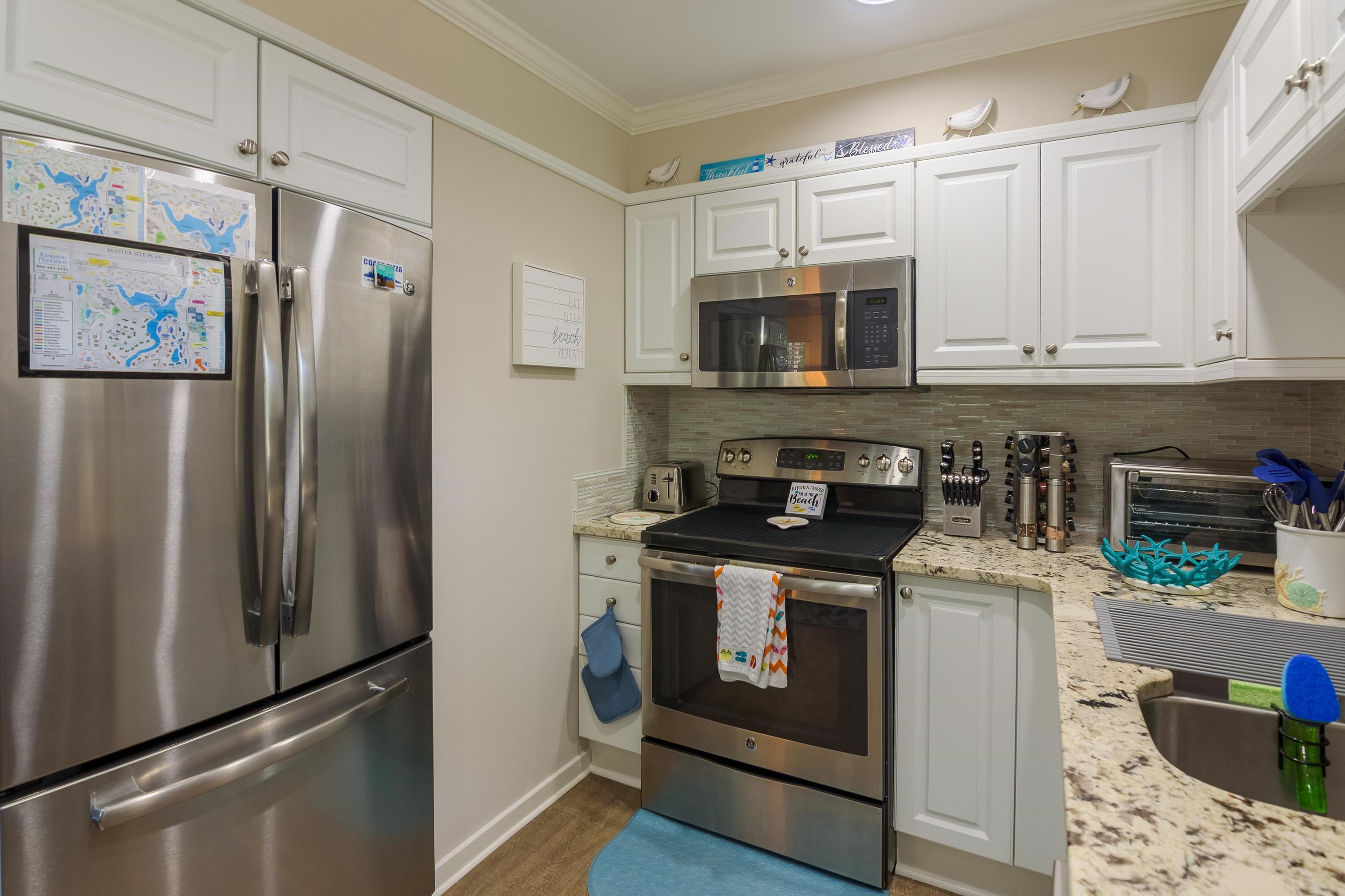 Kitchen with stainless steel appliances, white cabinets, granite counters, and a glass tile backsplash.