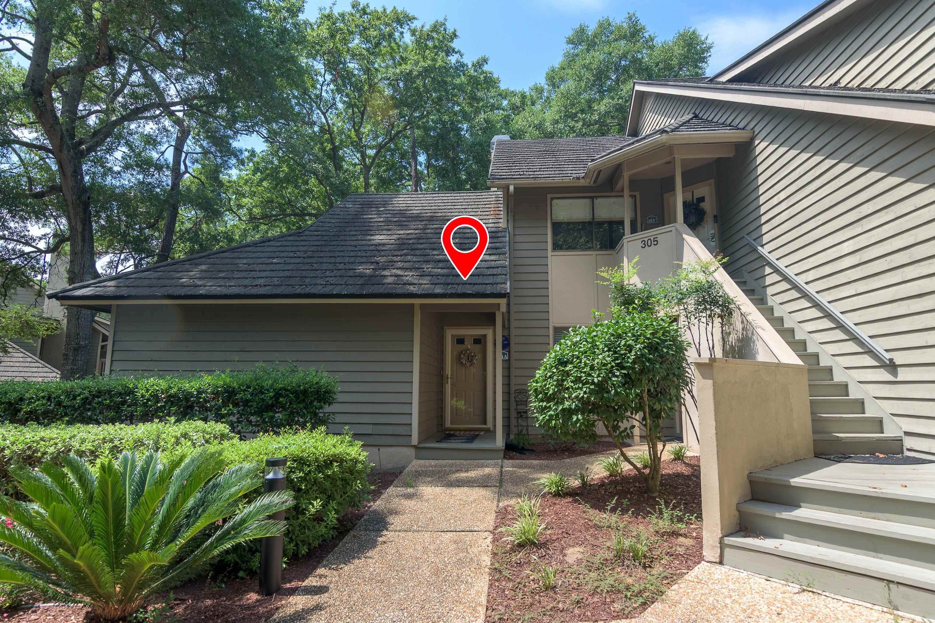 Condominium exterior with a landscaped entry, walkway, and elevated stairway.
