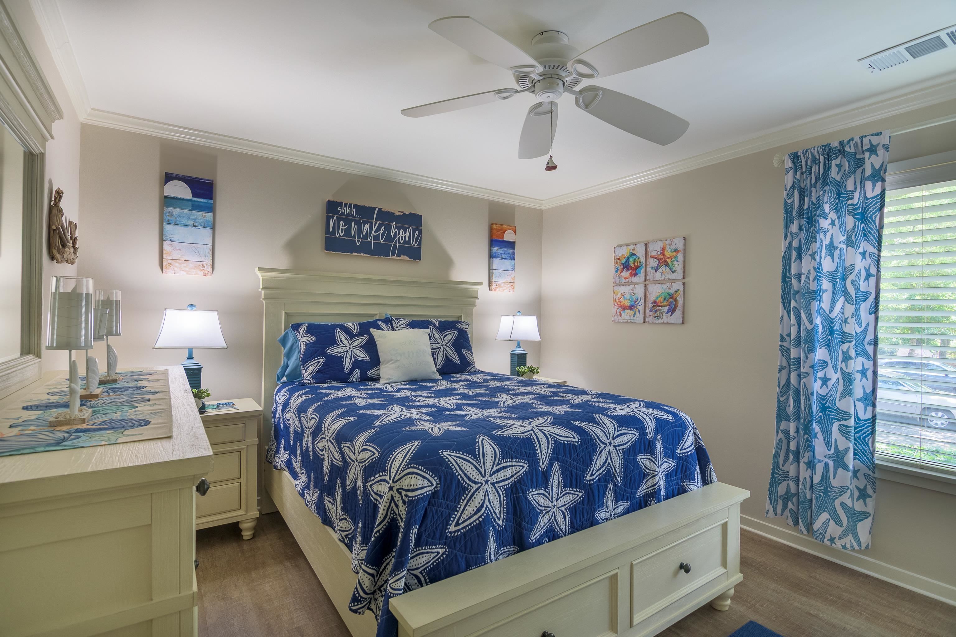 Bedroom with a blue starfish-patterned bedspread, matching curtains, and a pale wood bed frame.