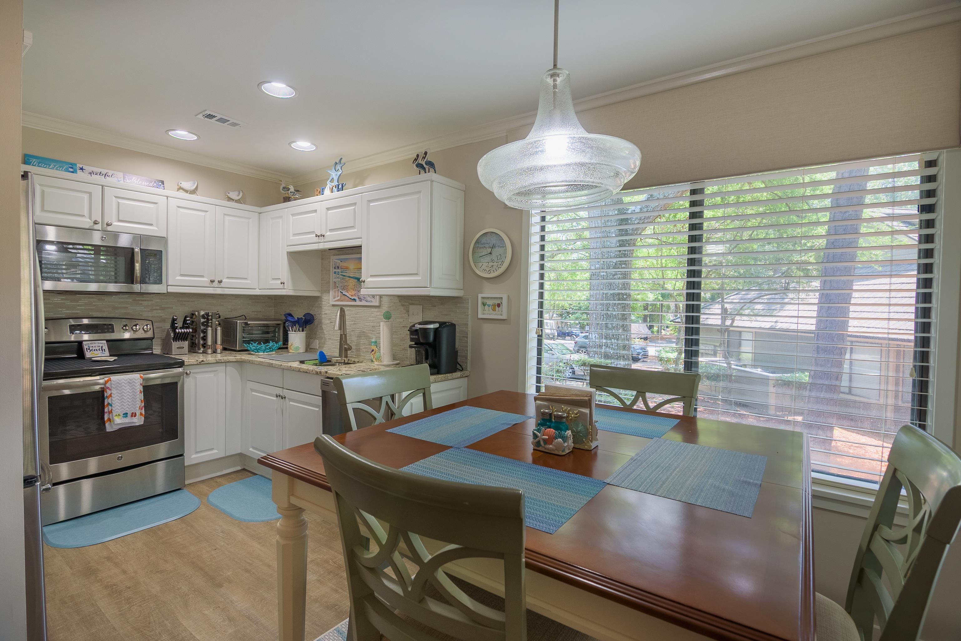 Kitchen and dining area with white cabinets, stainless steel appliances, and a large window.
