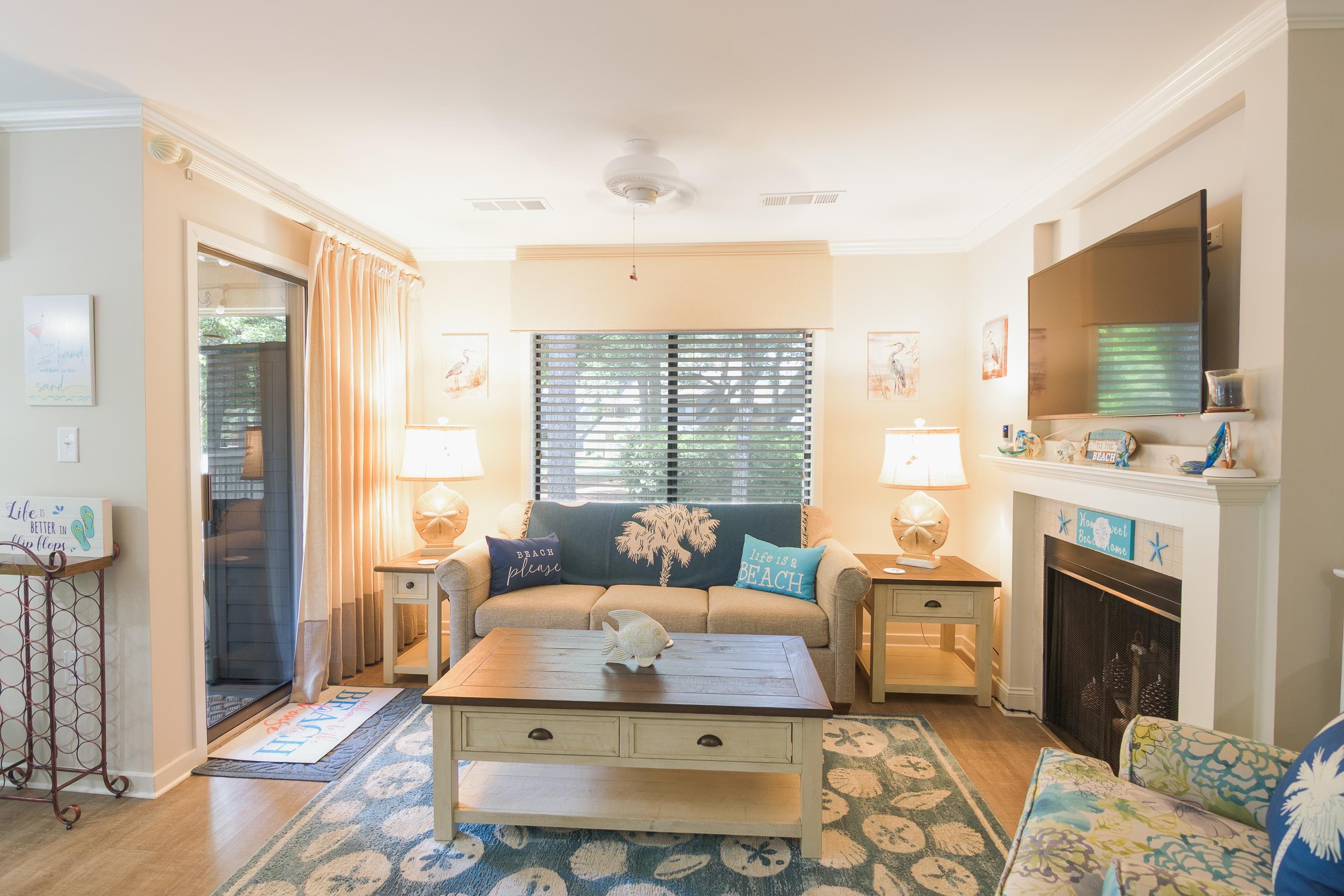 Furnished living room with a beach-themed sofa, sliding glass door, and fireplace.