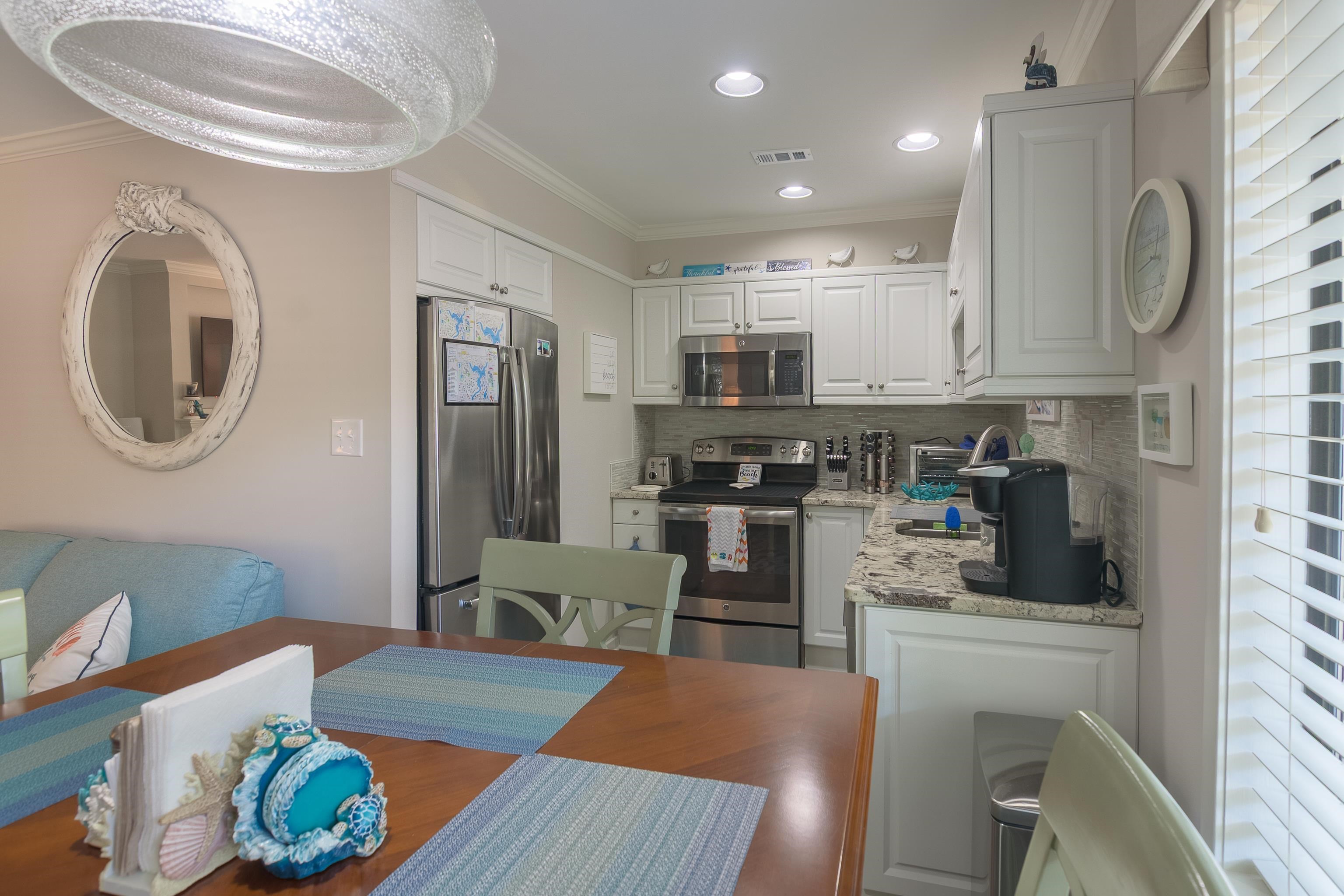 Kitchen and dining area with white cabinetry, stainless steel appliances, and a wood dining table.
