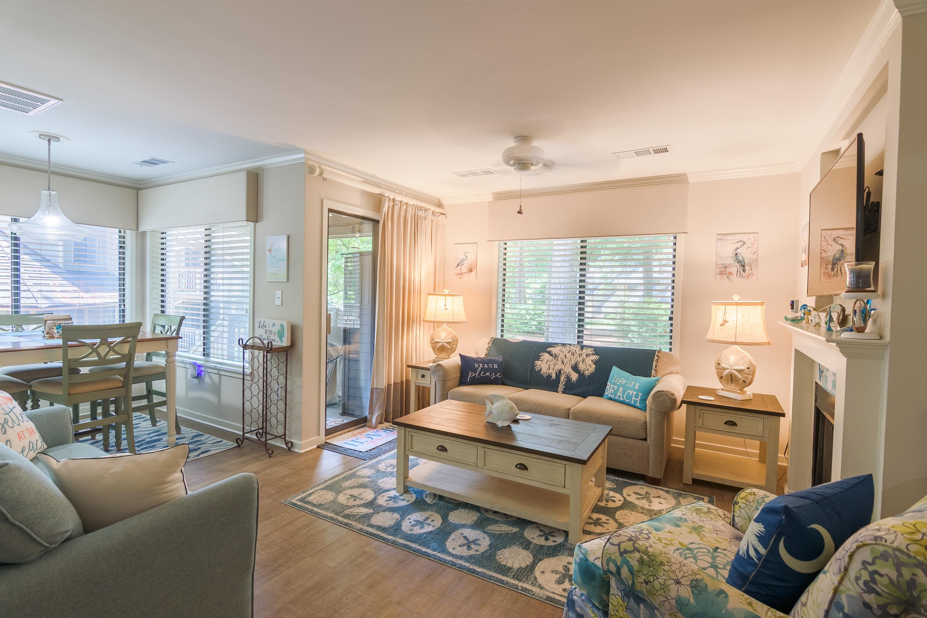 Furnished living room with beach-themed decor, a sofa, fireplace, and adjoining dining area.