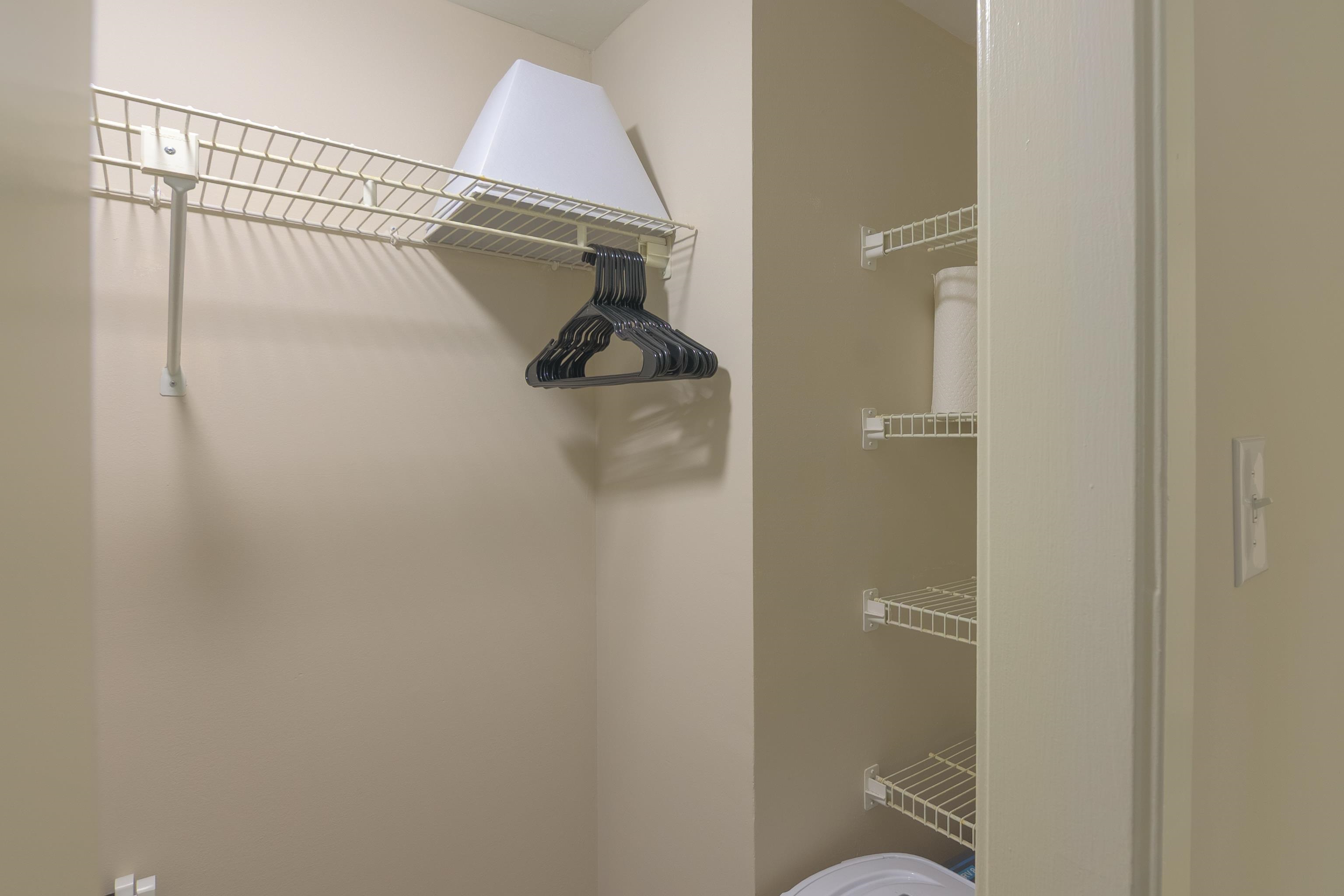 Walk-in closet with wire shelving, black hangers, and a glimpse of a washer.