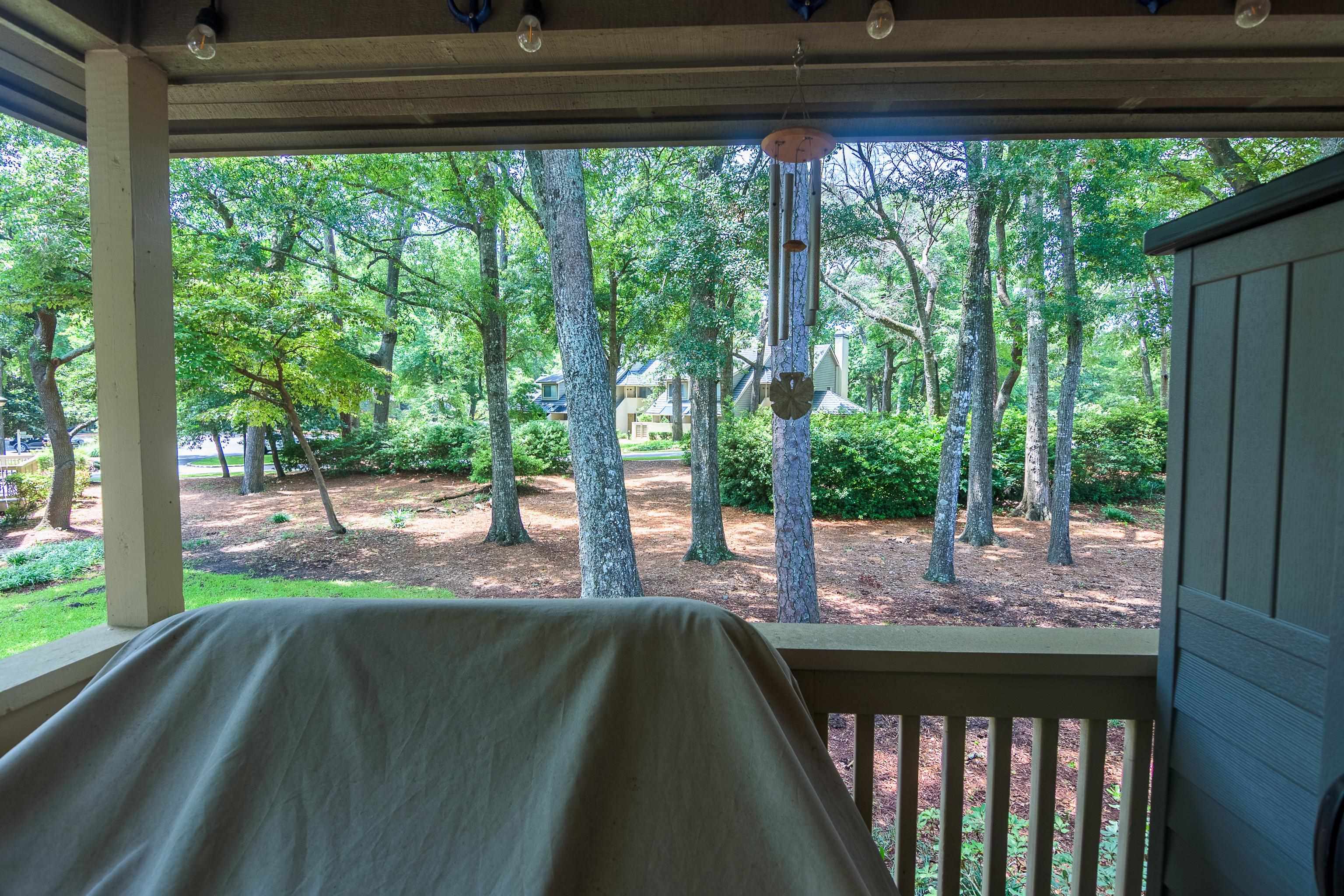 Covered porch overlooking a shady, tree-filled residential courtyard.