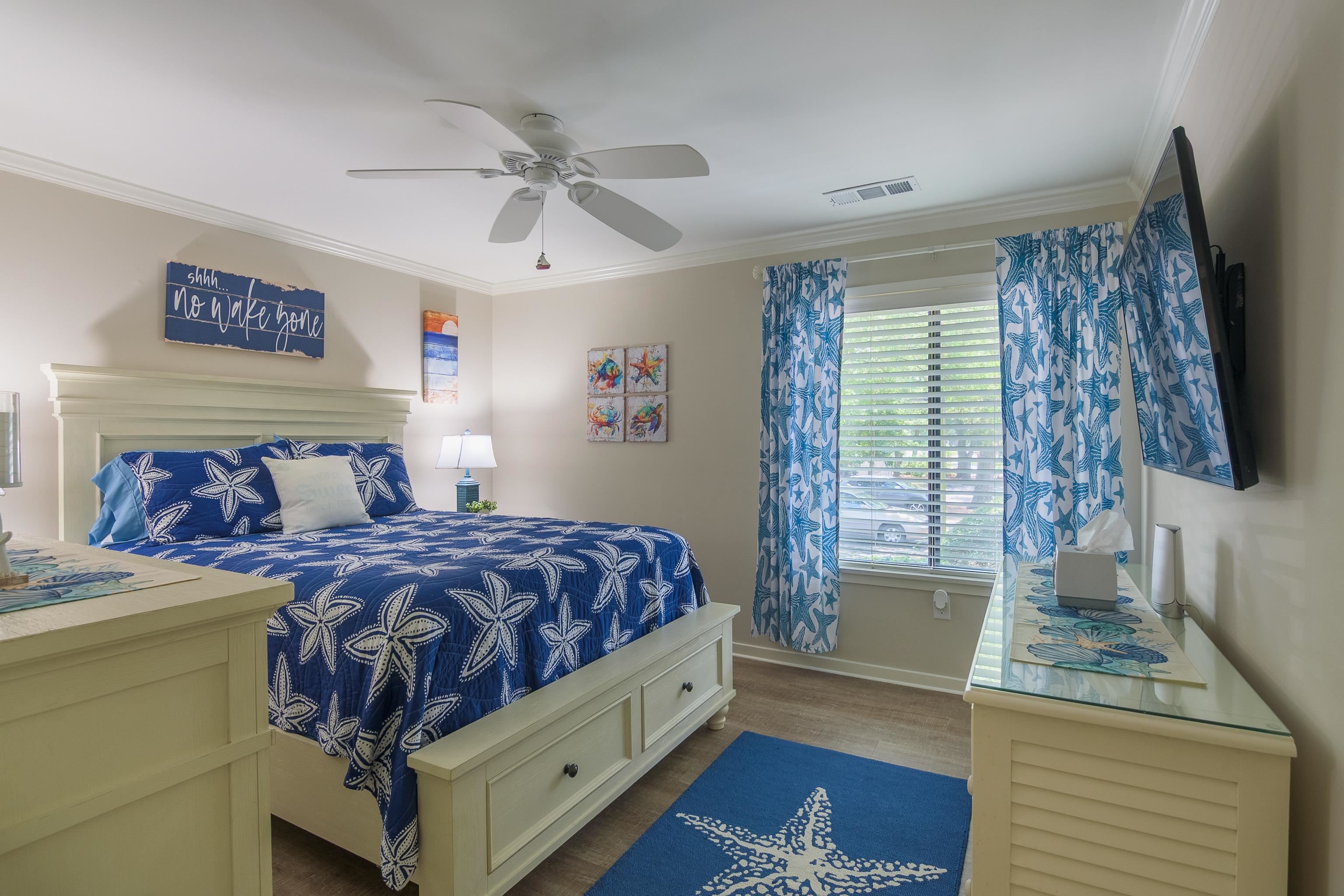 Bedroom with a navy starfish-patterned bedspread, matching curtains, and a bright window.