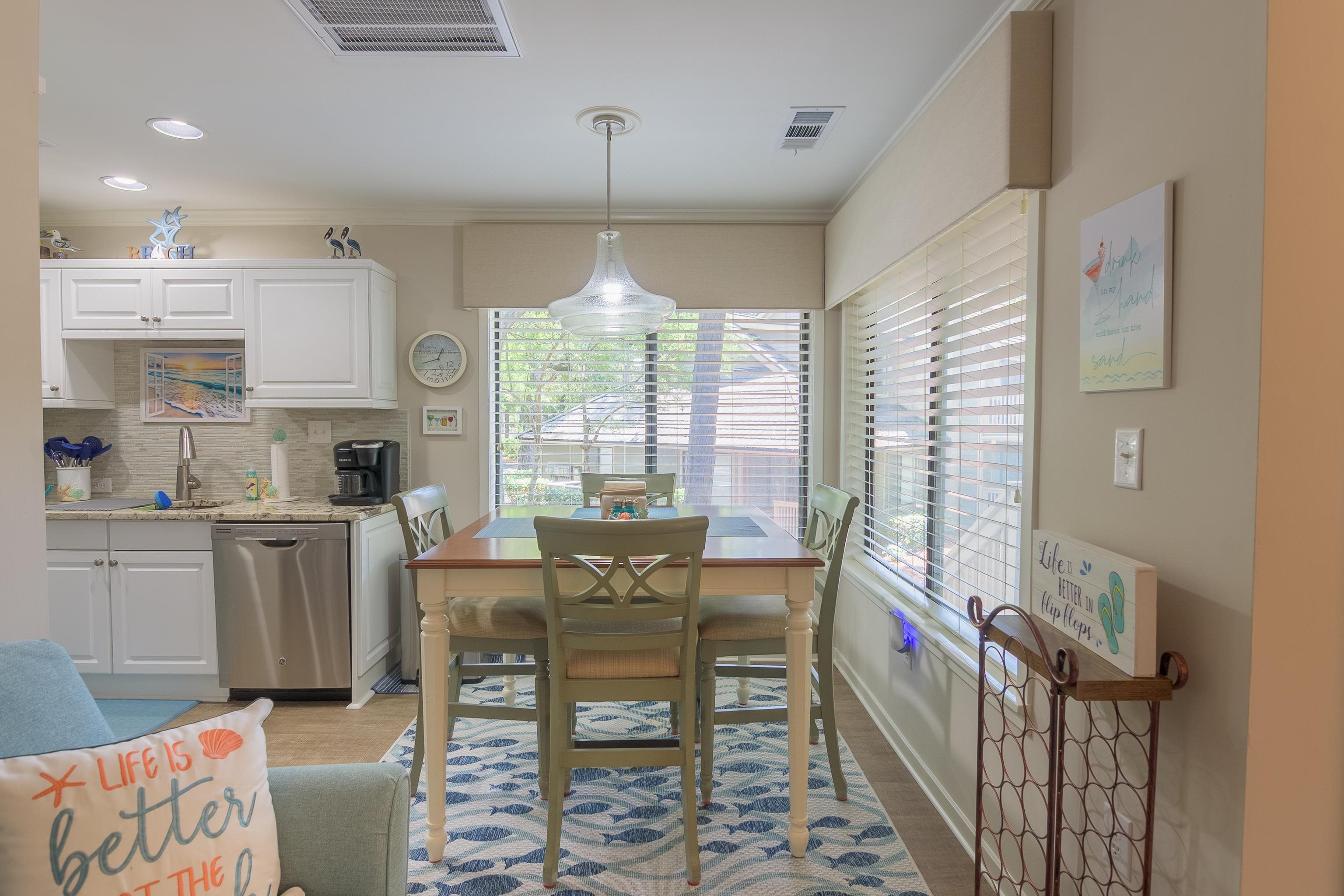Kitchen and dining area with white cabinets, a dining table, and large windows with blinds.