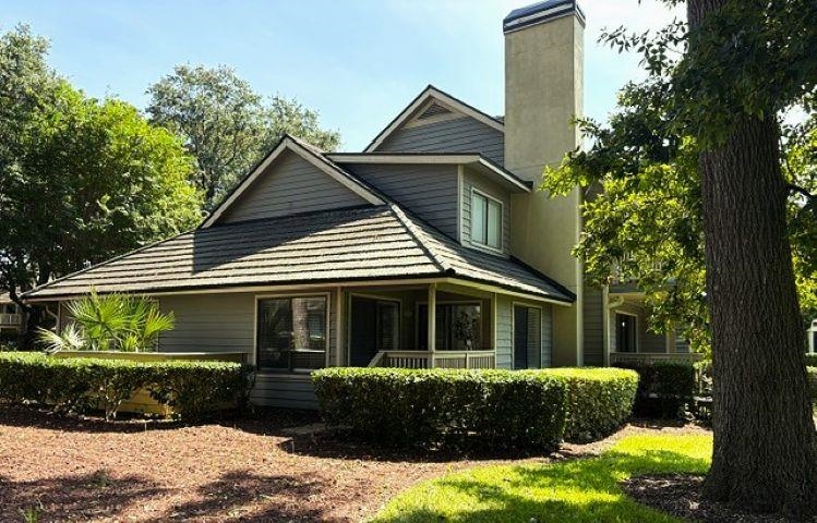 Gray two-story home with multiple gables, a tall chimney, and a covered porch.