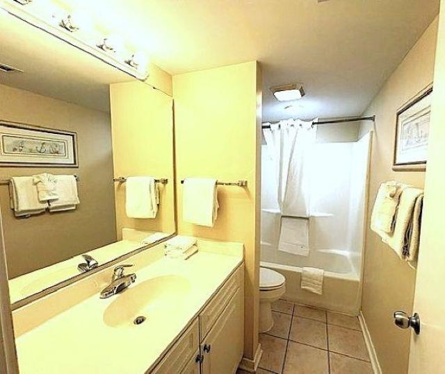 Bathroom with a long vanity, mirrored wall, and tub-shower combination.