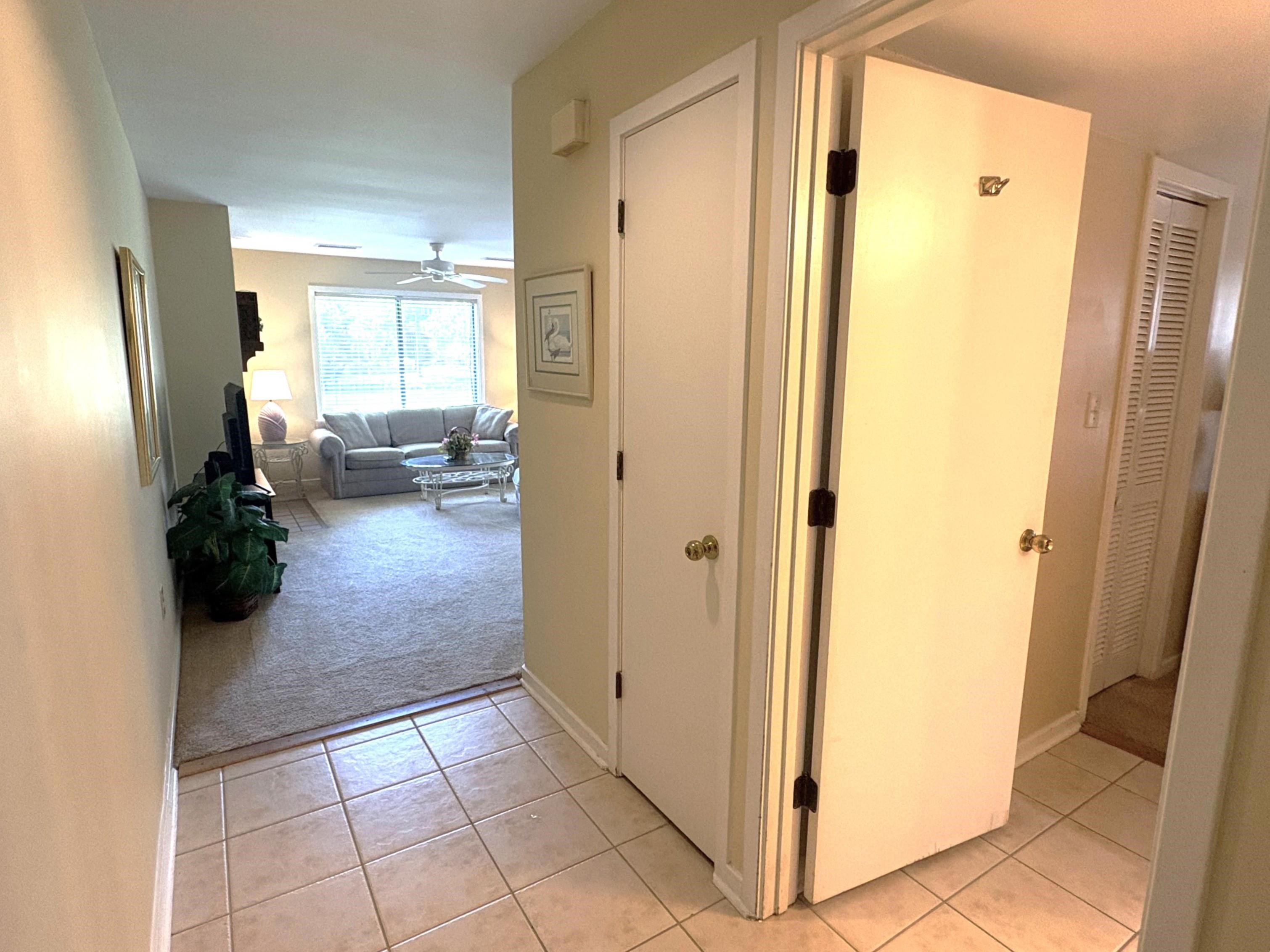 Tiled entry hallway opening to a furnished living room with a gray sofa and large window.