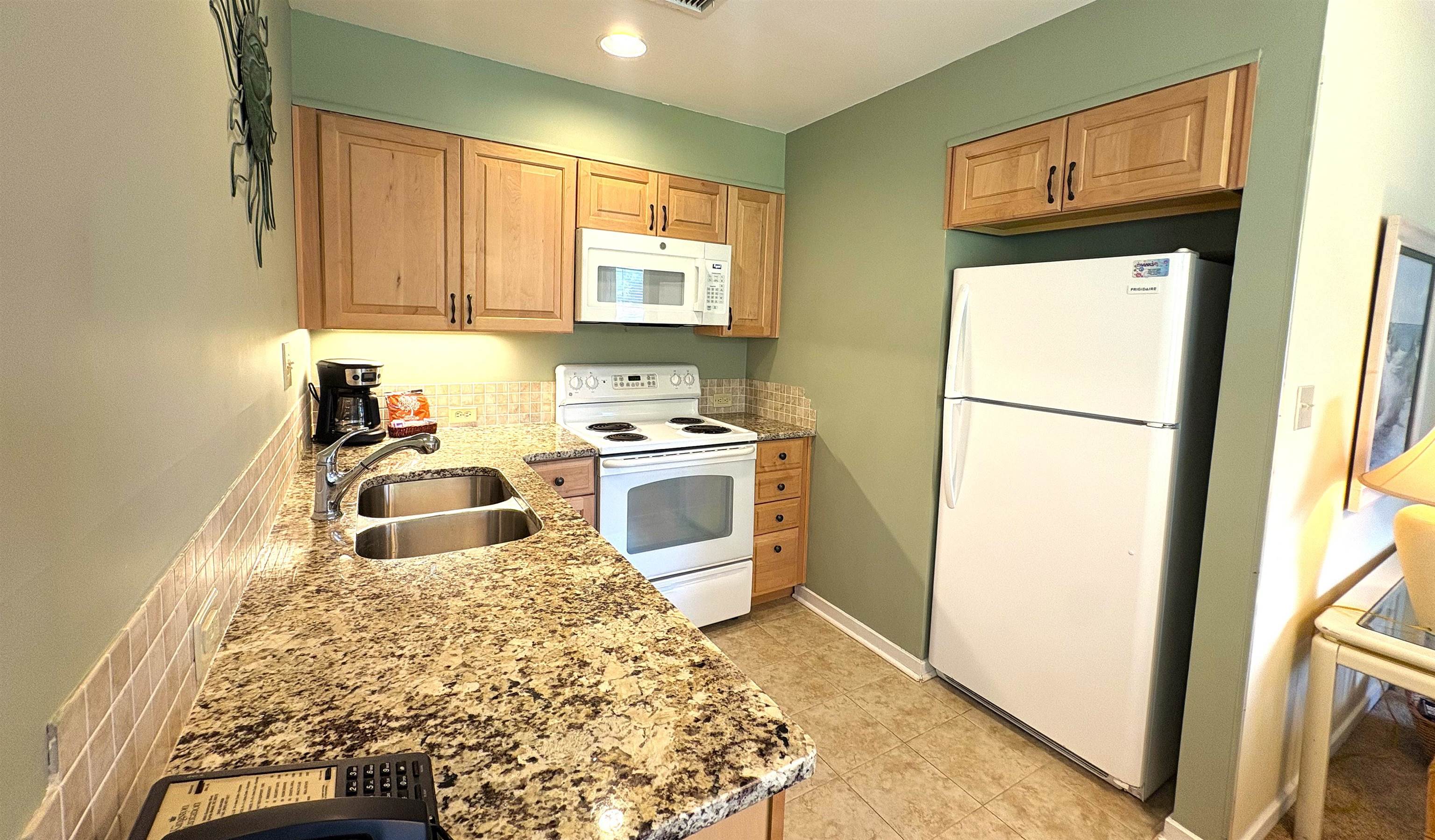 Kitchen with granite counters, wood cabinets, white appliances, and a double-basin sink.
