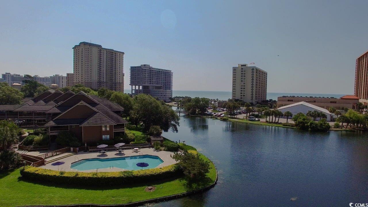 Aerial view of a waterfront pool and high-rise buildings with the ocean beyond.