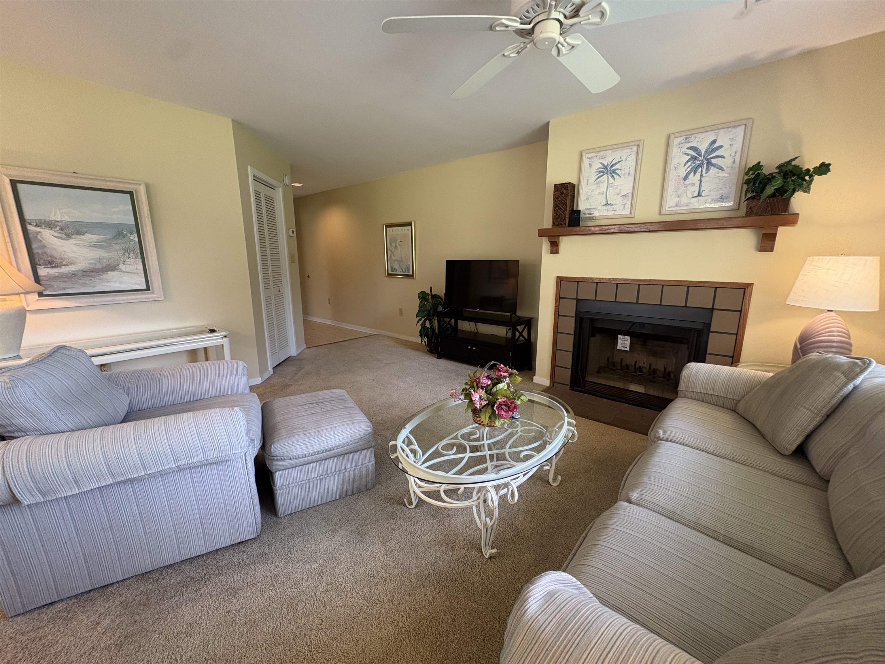 Living room with two sofas, a glass coffee table, and a tiled fireplace.