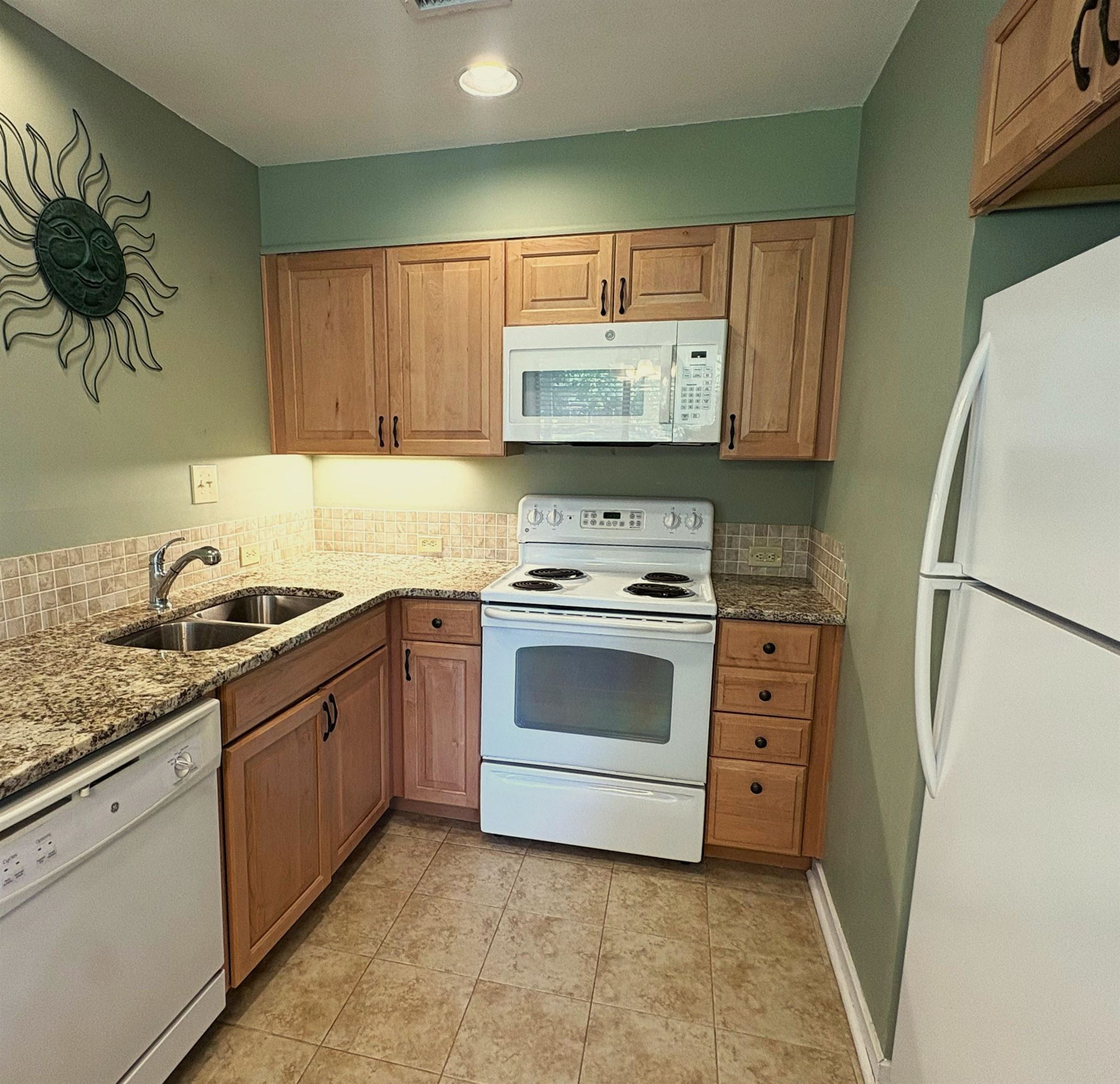 Kitchen with wood cabinets, granite countertops, and white appliances.
