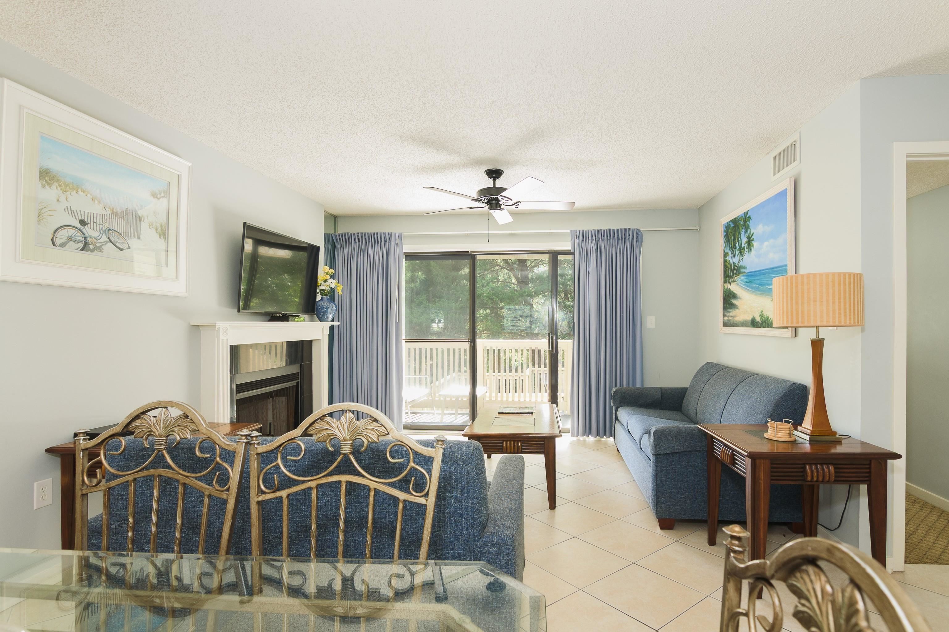 Furnished living room with a fireplace, blue sofas, and sliding glass doors to a deck.