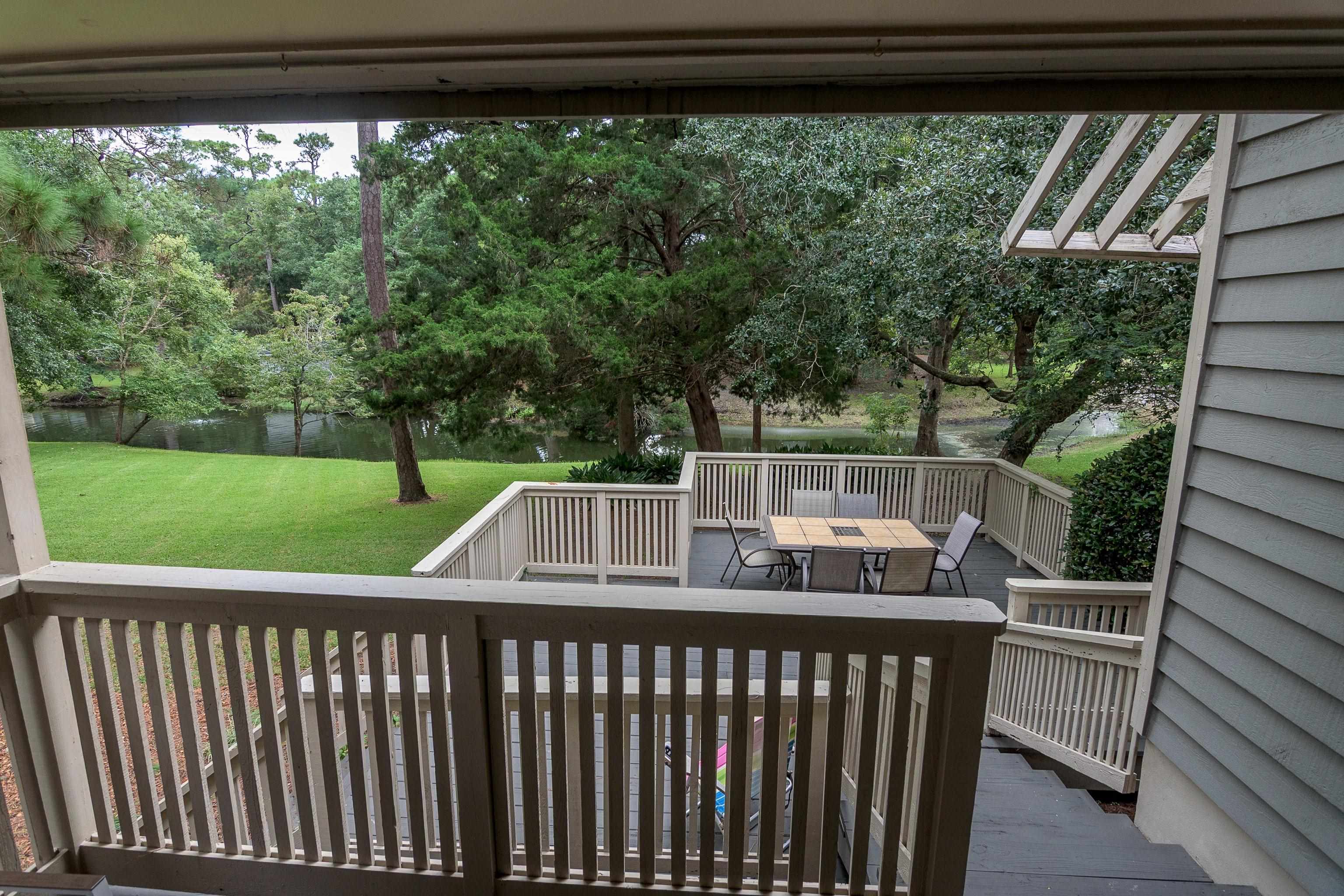 Multi-level deck with outdoor dining table overlooking a tree-lined pond.