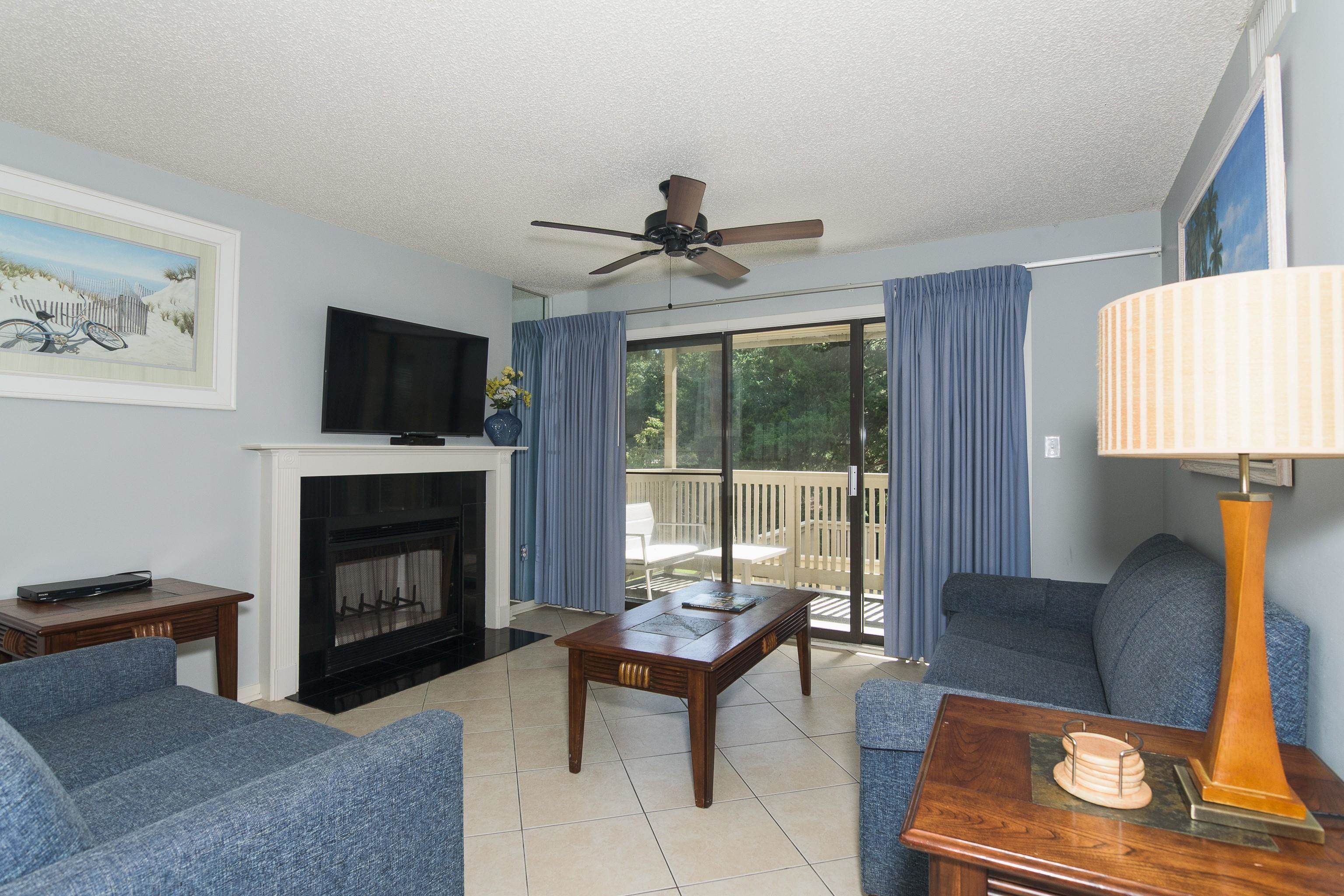 Living room with blue sofas, a fireplace, and sliding doors to a balcony.