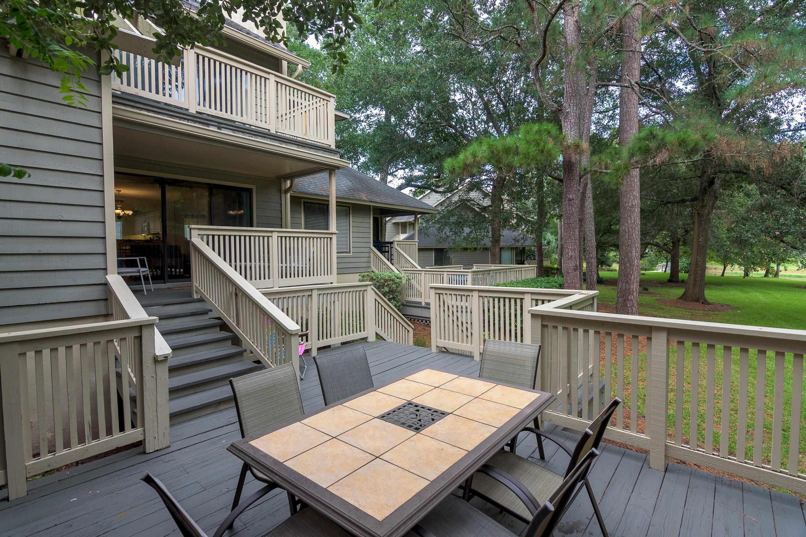 Condominium decks and stairs with a tiled patio table among mature trees.