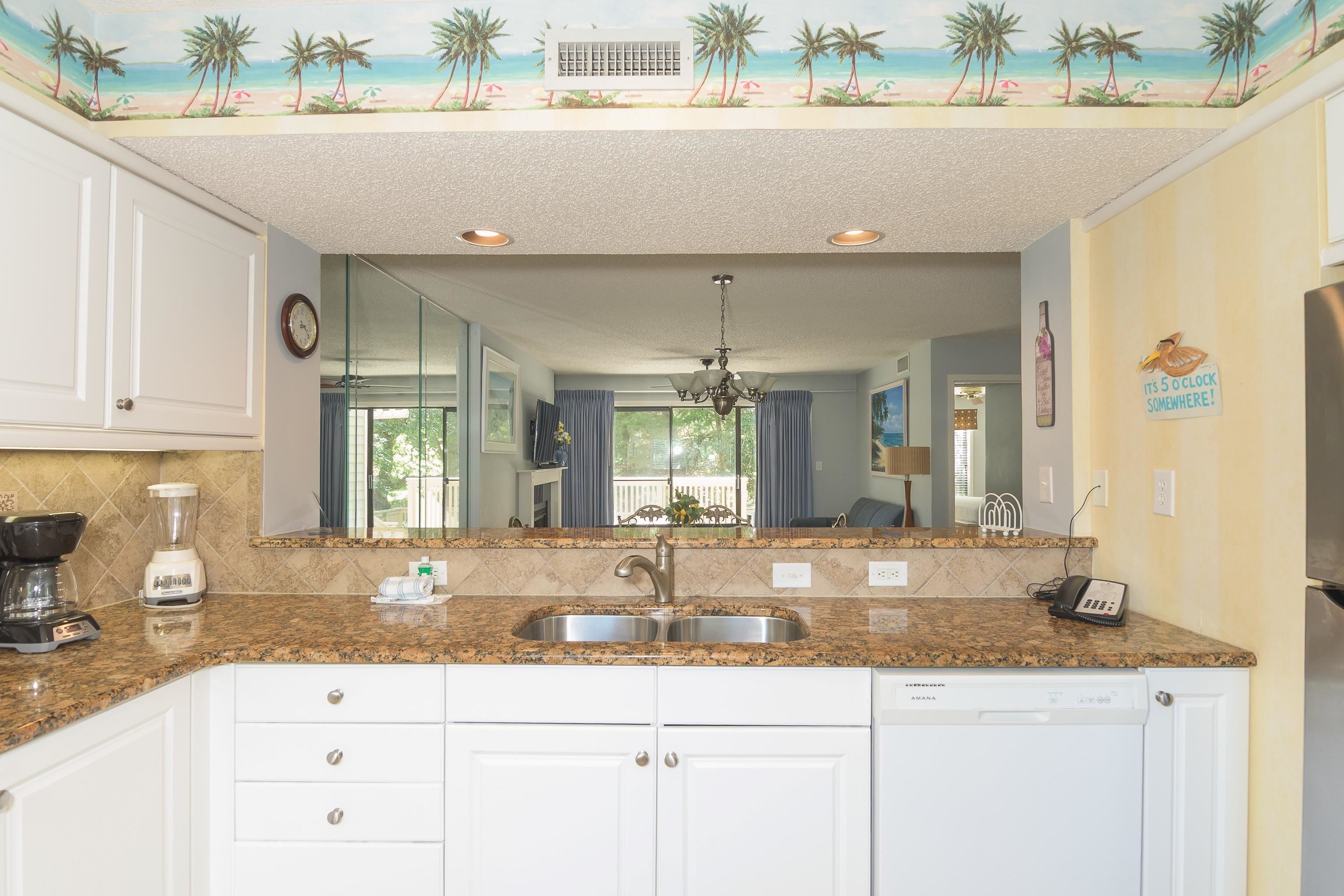 Condo kitchen with a stone breakfast bar, double sink, white cabinets, and a tropical ceiling mural.