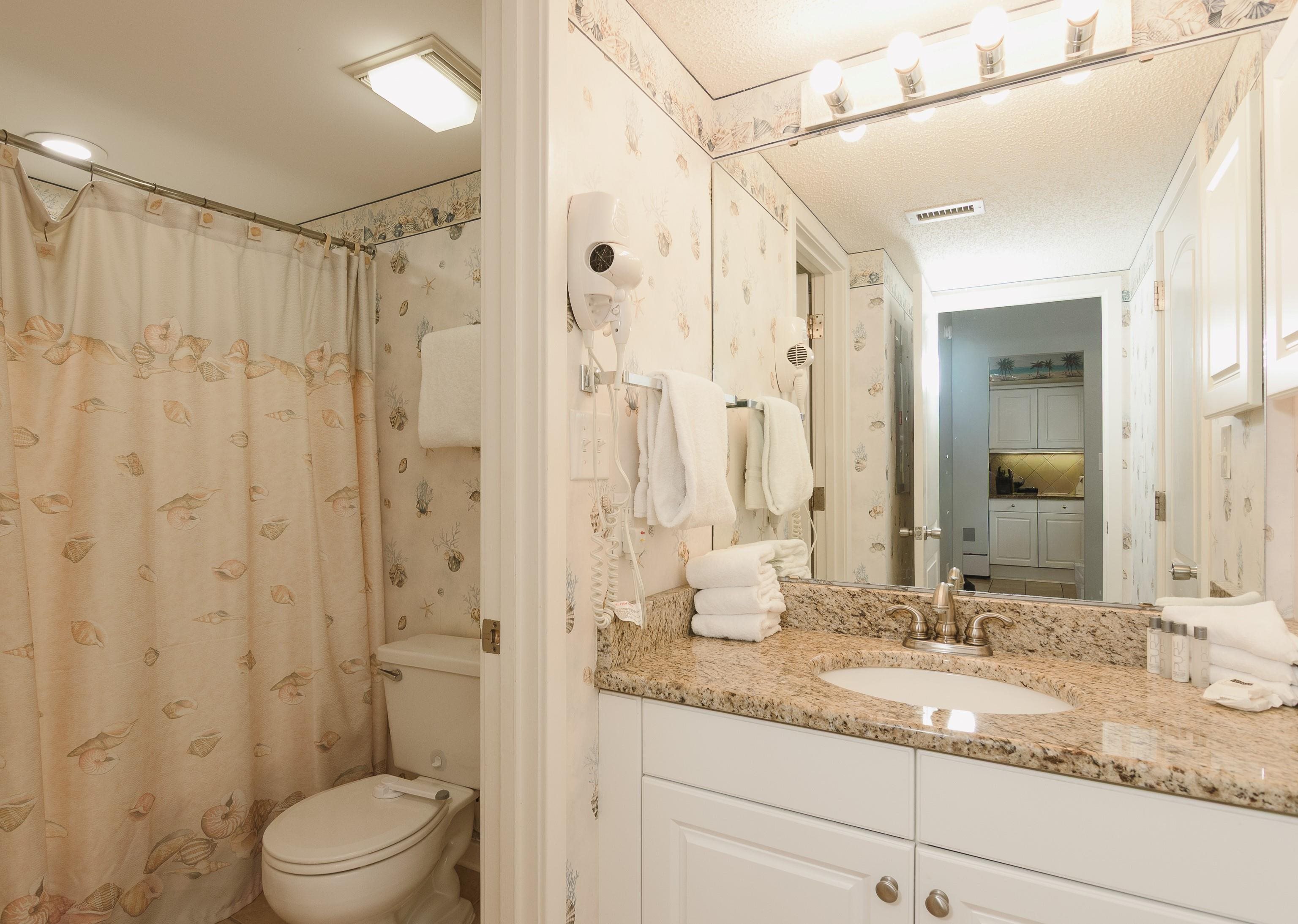 Bathroom with shell-patterned decor, a granite vanity, and a shower curtain.