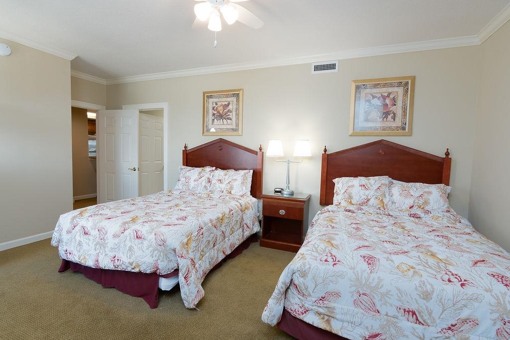 Bedroom with two floral-covered beds, dark wood headboards, and a nightstand between them.