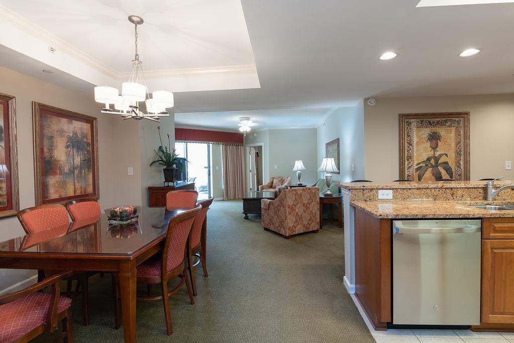 Open-plan condo dining and living area with red chairs and a granite kitchen island.