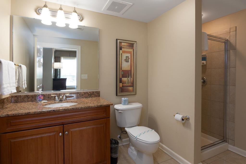 Bathroom with a wood vanity and granite counter beside a glass-enclosed tiled shower.