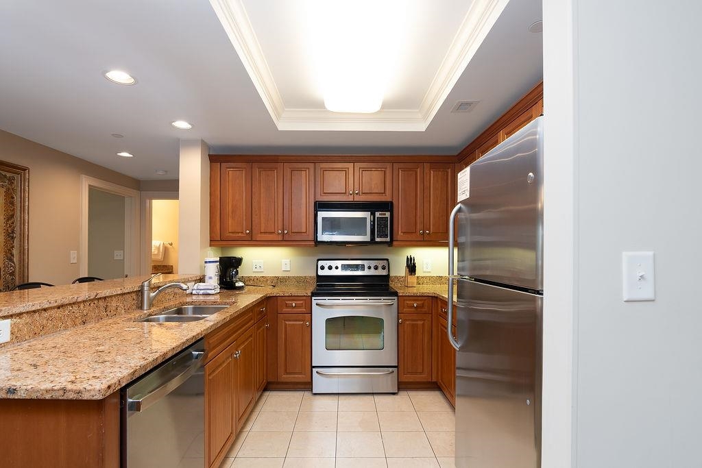 Condo kitchen with wood cabinets, granite counters, and stainless steel appliances.