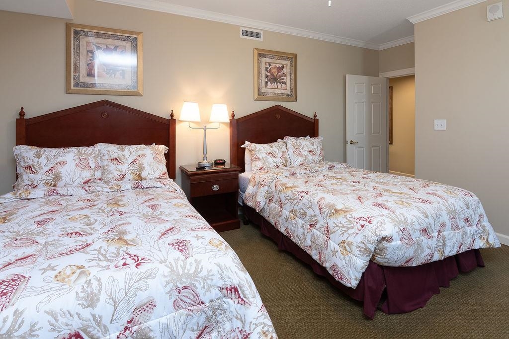 Bedroom with two beds in matching floral bedding and dark wood headboards.