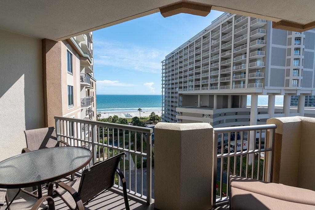Furnished condominium balcony overlooking the ocean between neighboring beachfront towers.