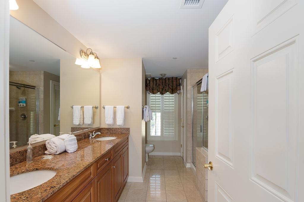 Bathroom with a double-sink granite vanity and tiled shower.