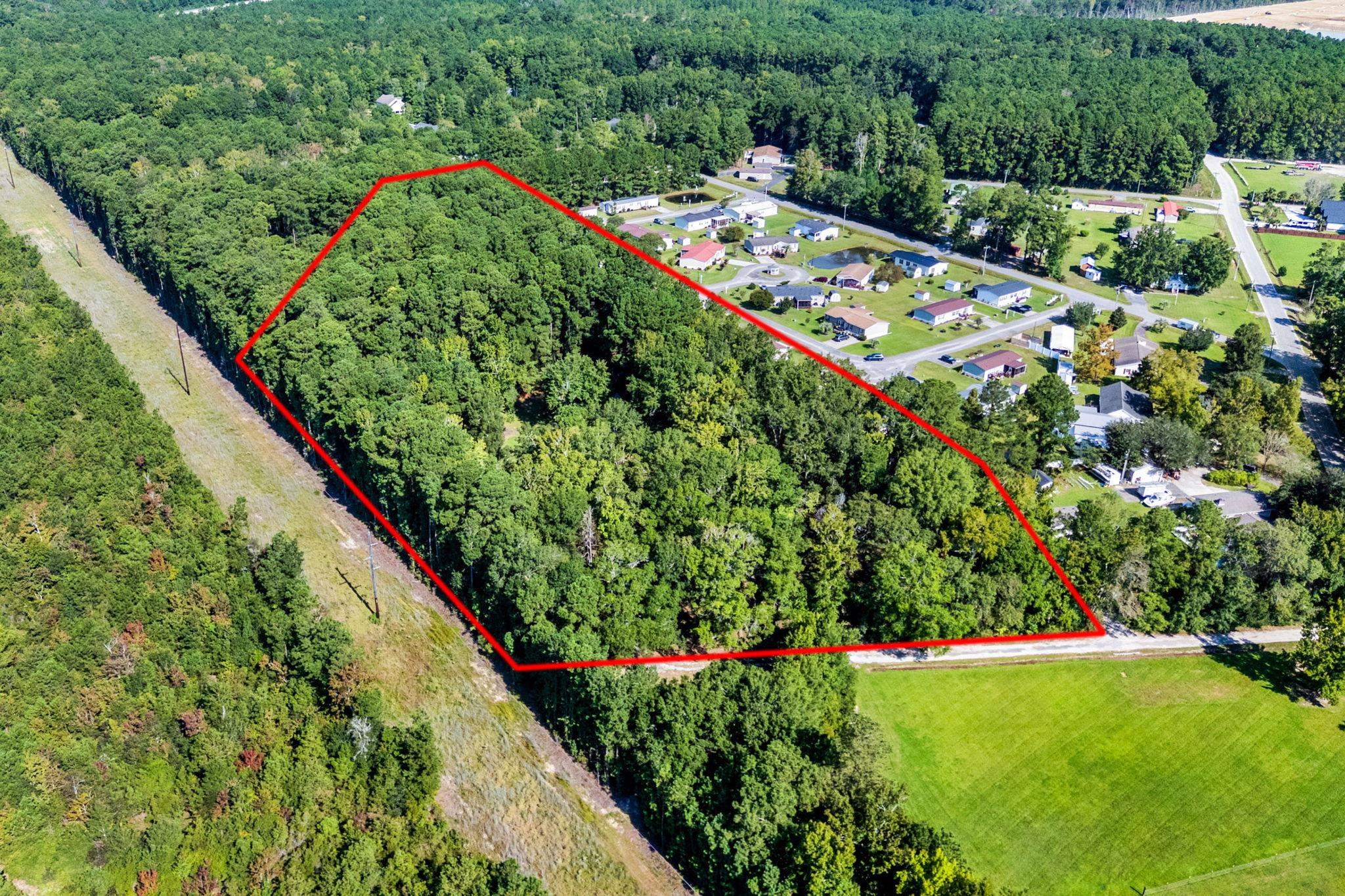 Aerial view of a wooded parcel outlined in red beside a residential neighborhood.
