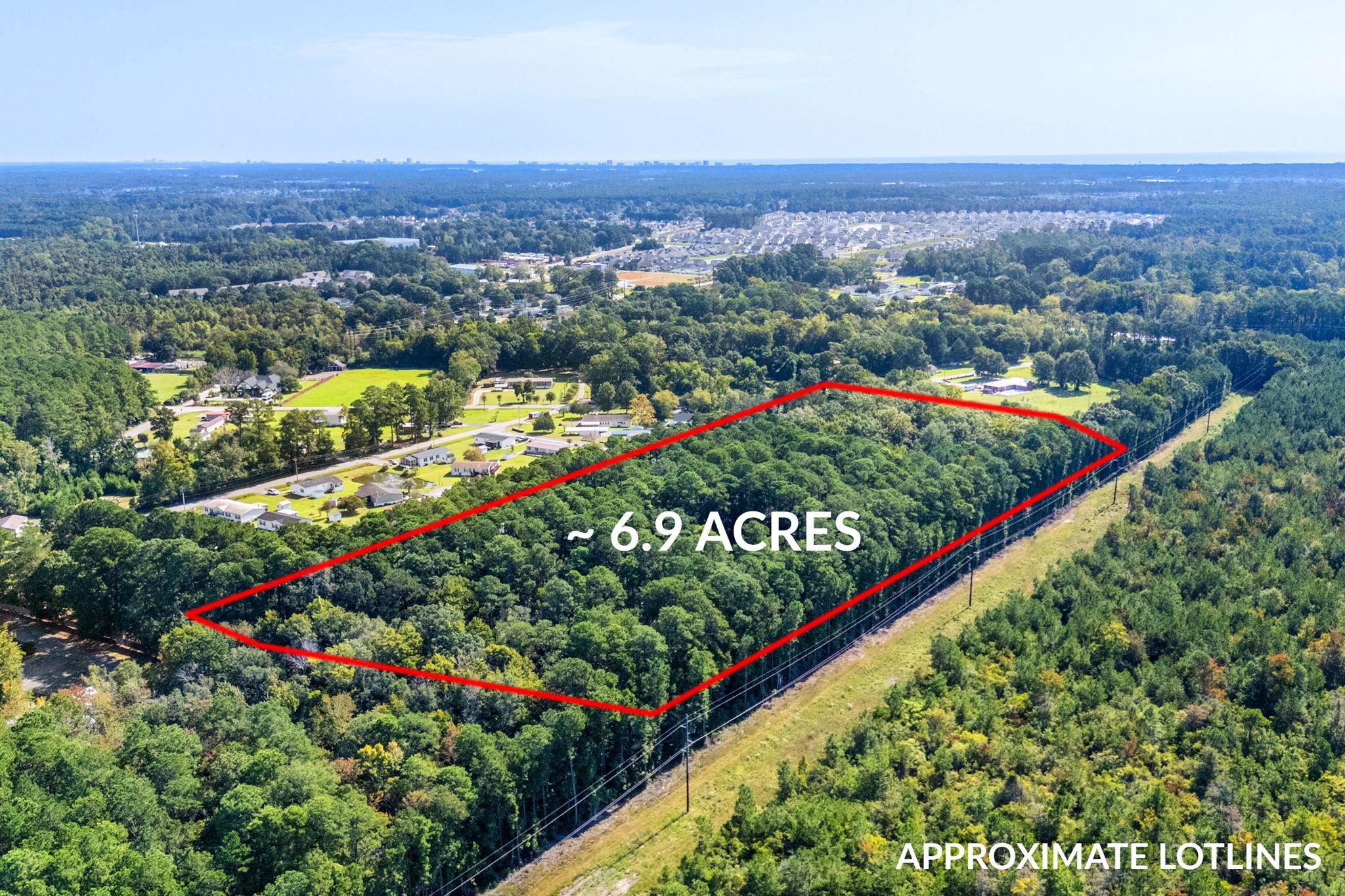 Aerial view of a wooded 6.9-acre parcel outlined in red, with approximate lot lines.