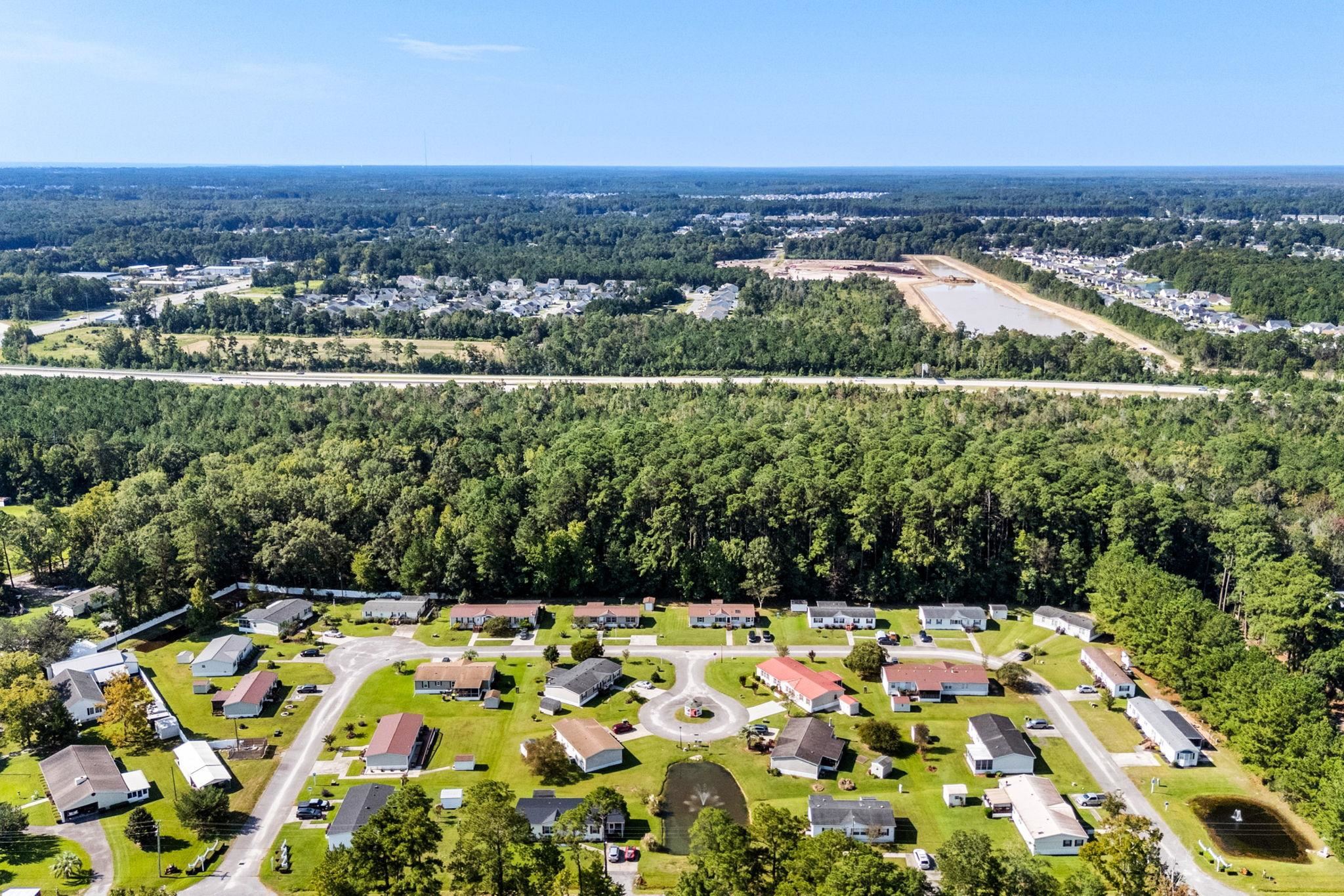 Aerial view of homes around cul-de-sacs, with ponds and woods nearby.