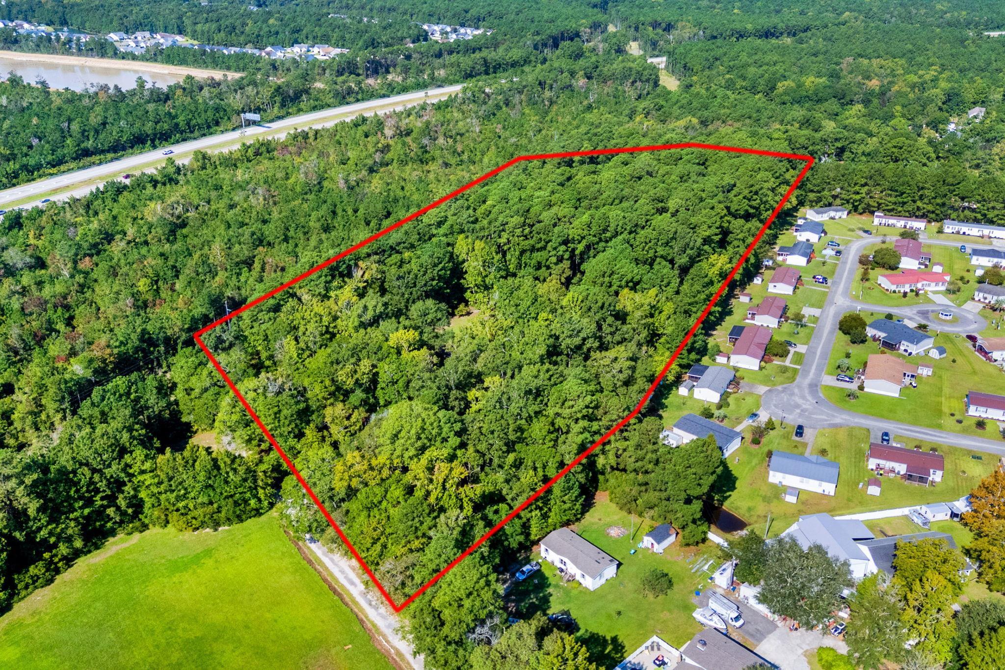 Wooded property outlined in red beside a neighborhood of homes.