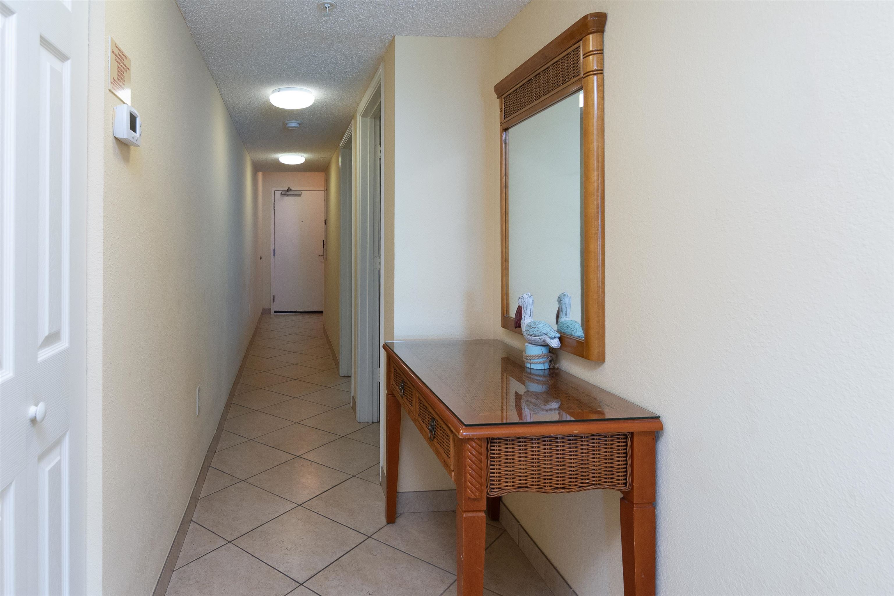 Condominium hallway with diagonal tile flooring and a wooden console table beneath a mirror.