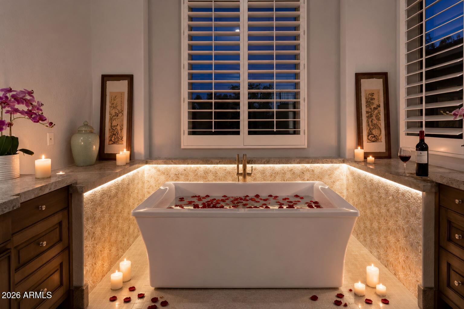 Freestanding soaking tub with rose petals in a candlelit tiled alcove beneath shuttered windows.