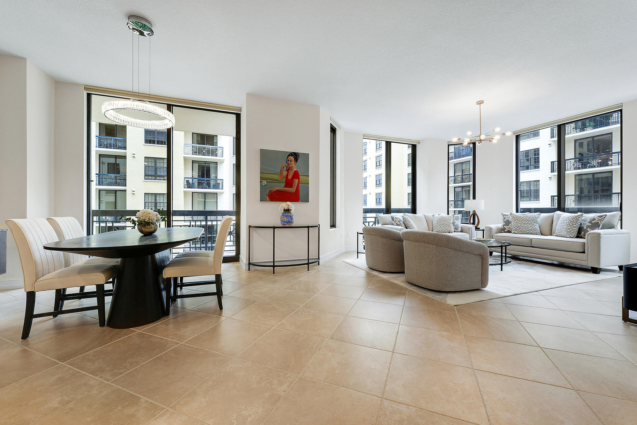 Open-plan condo living and dining area with large windows, modern seating, and tile floors.