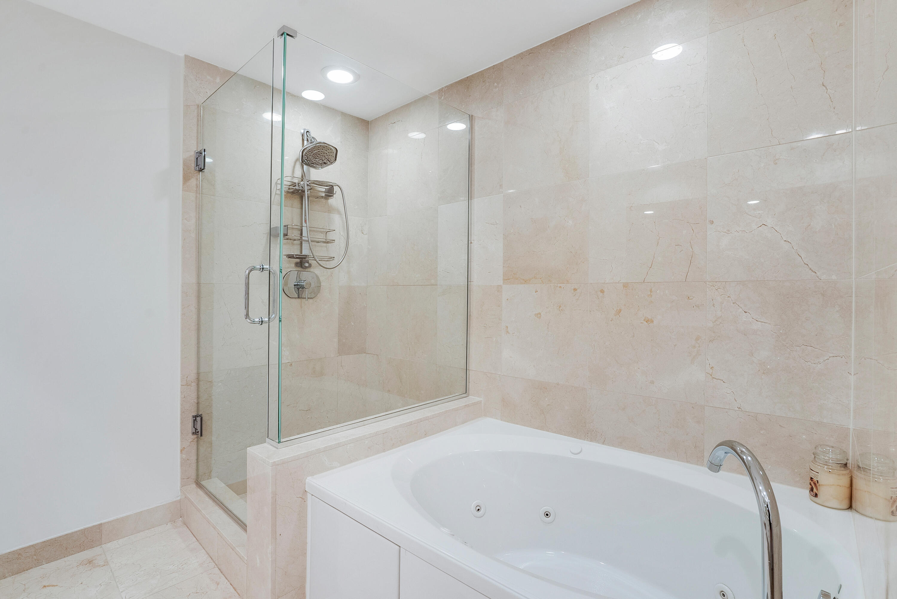 Bathroom with a glass-enclosed shower and marble-tiled jetted soaking tub.