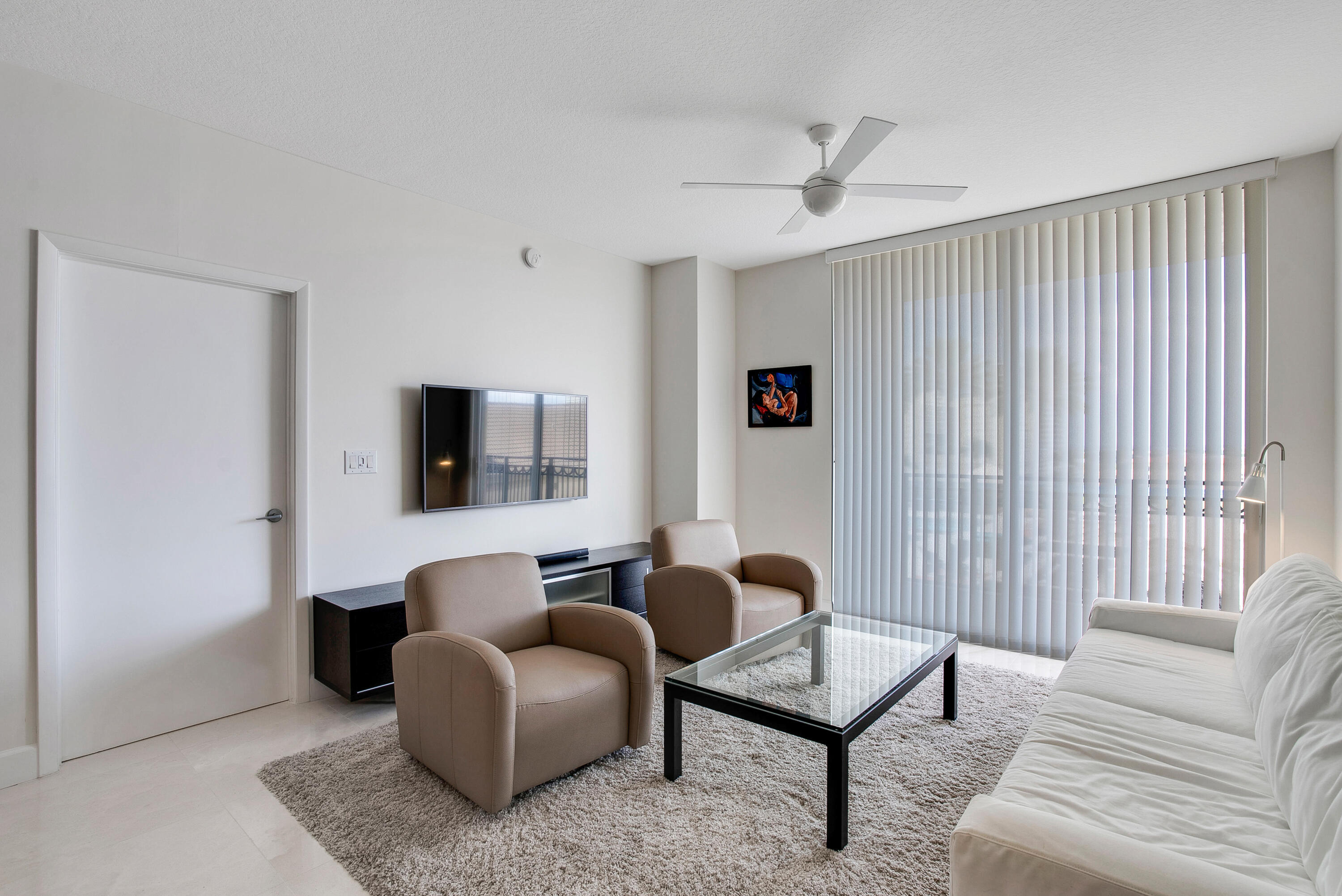 Living room with tan armchairs, a white sofa, and a glass coffee table.