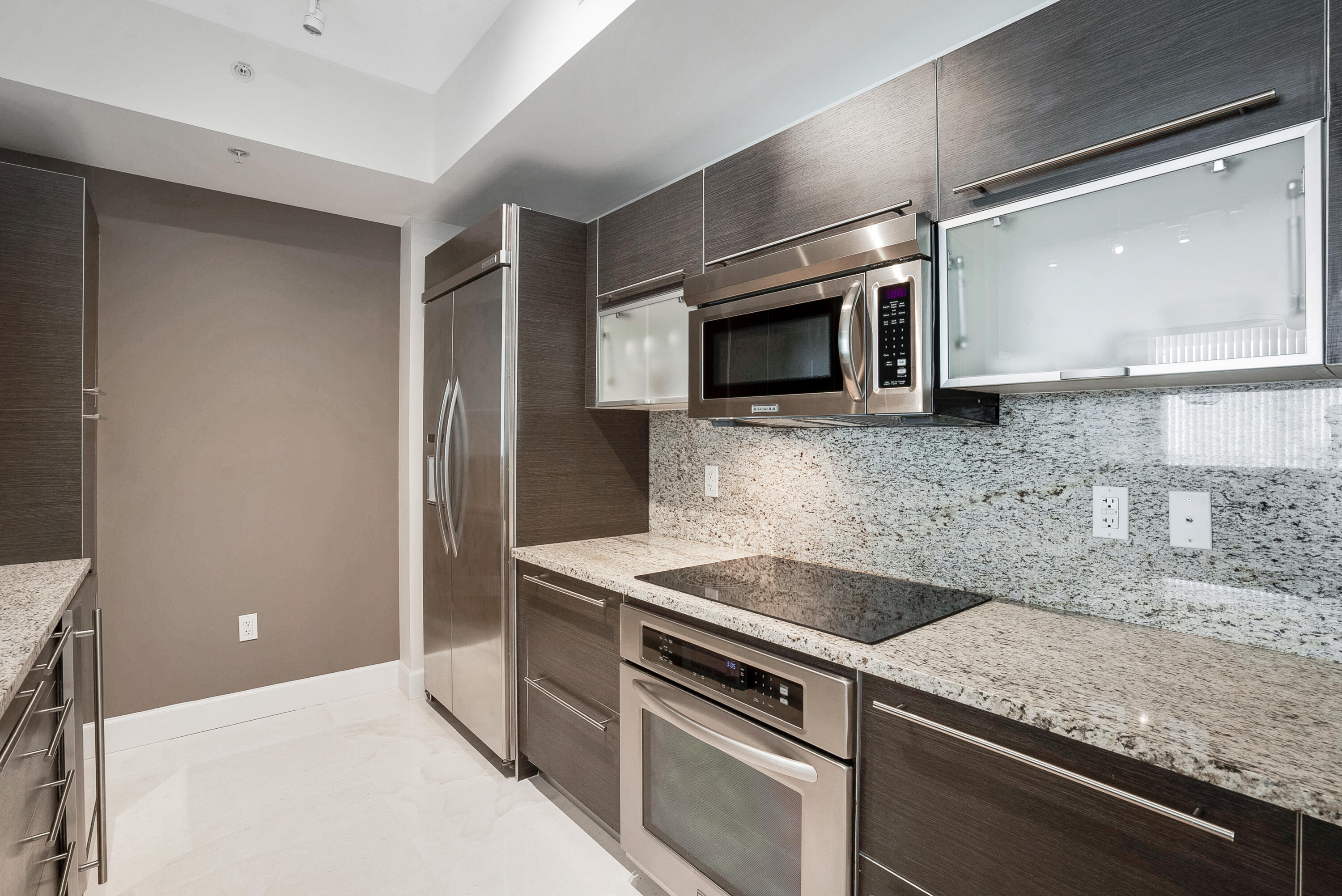 Modern kitchen with dark cabinets, stainless steel appliances, and granite counters.