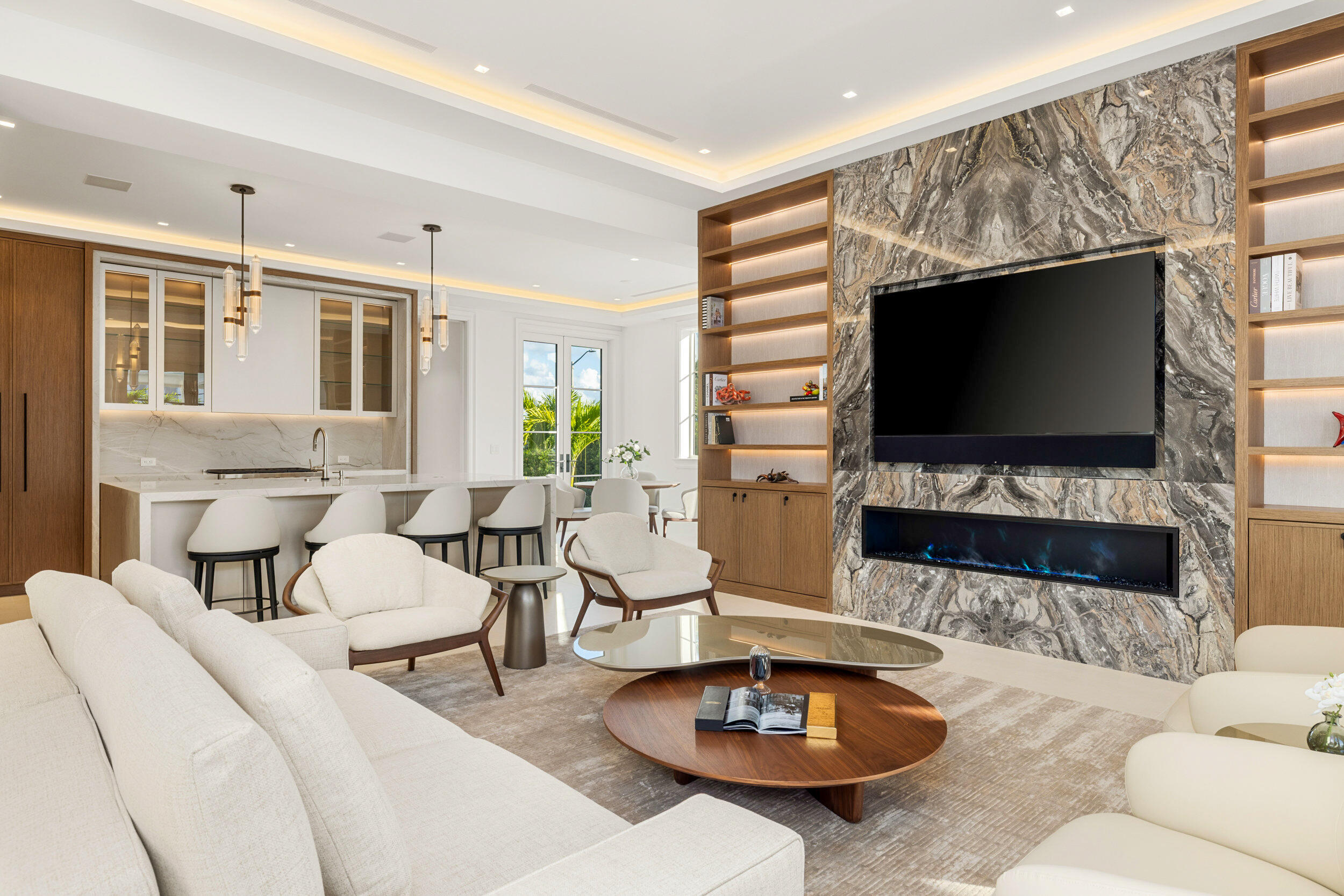 Open-plan living room with a dramatic stone fireplace, built-in shelves, and a kitchen island.