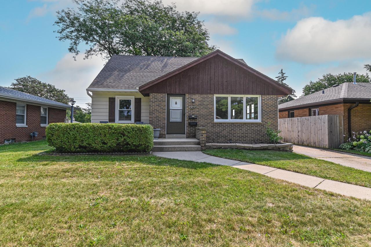 Single-story brick and siding house with a dark wood front gable, trimmed hedge, lawn, and concrete walkway.