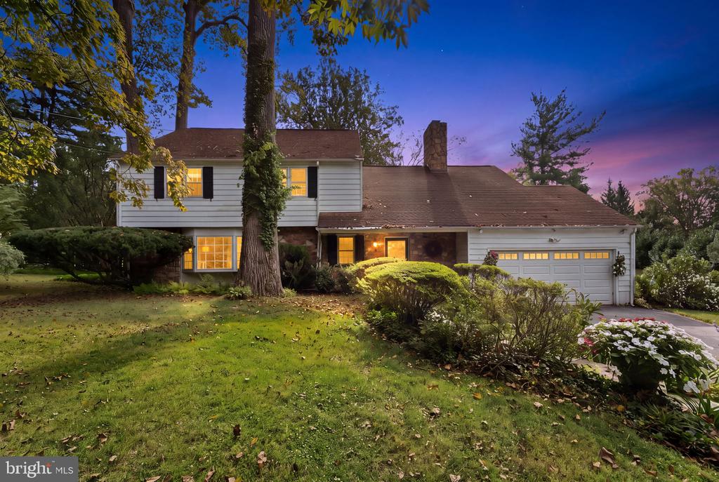Two-story house with attached garage, landscaped lawn, and illuminated windows at dusk.