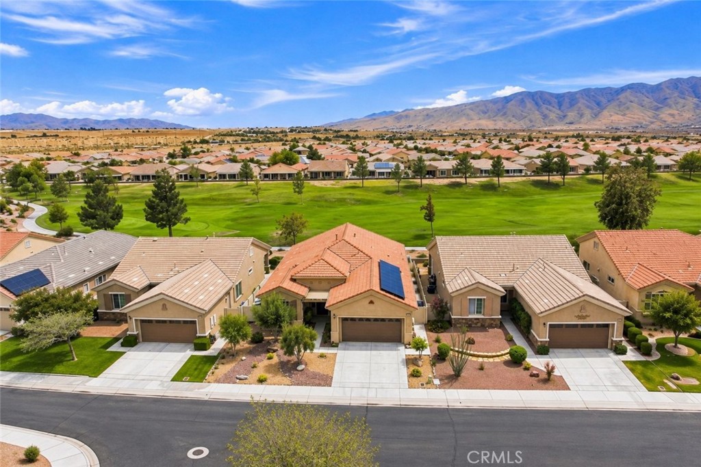 Aerial view of homes beside a green park, with mountains in the distance.