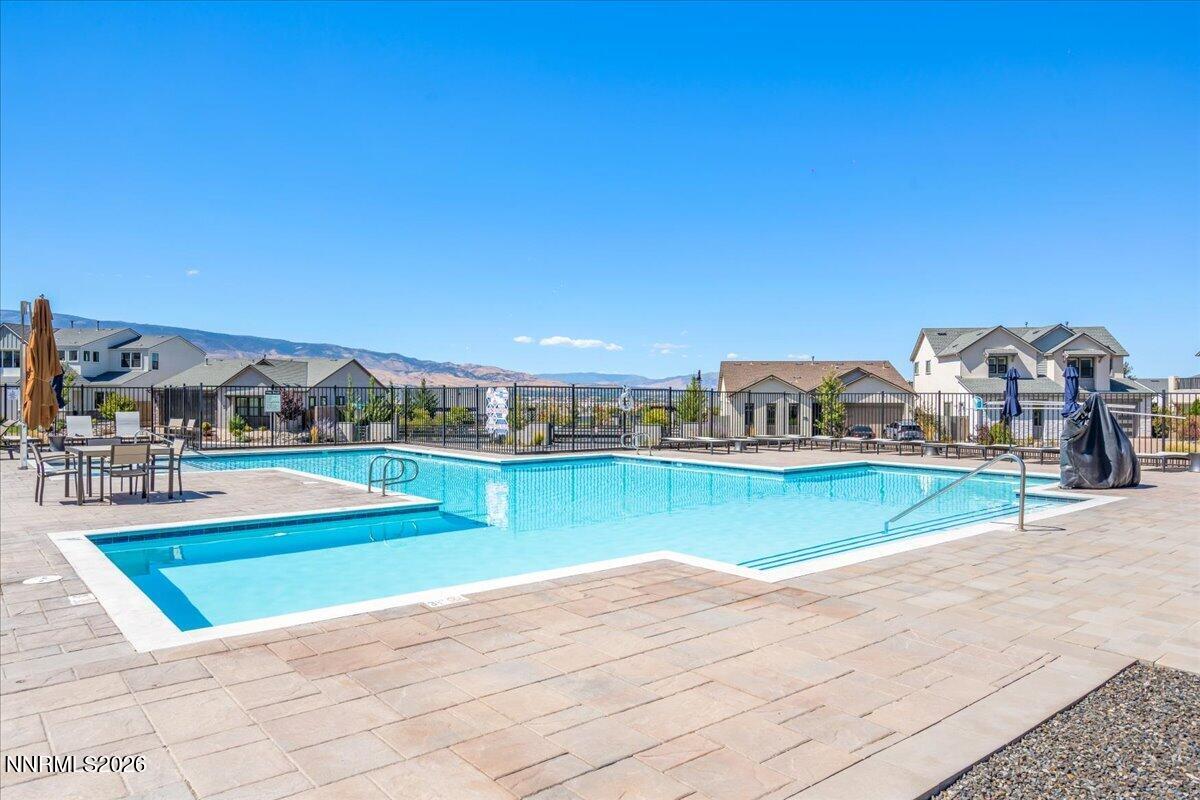 Community swimming pool with a shallow entry, paved deck, and distant mountain views.