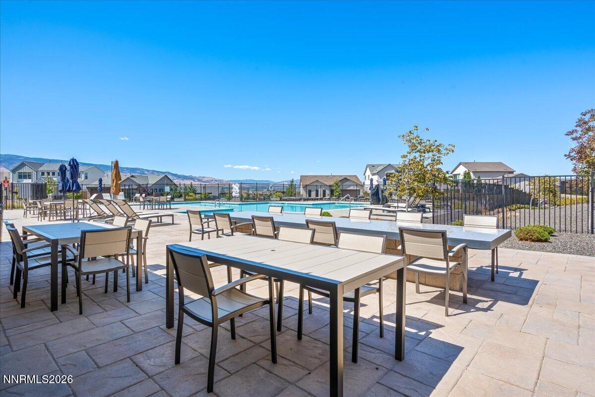 Community pool and patio with outdoor dining tables and distant mountain views.